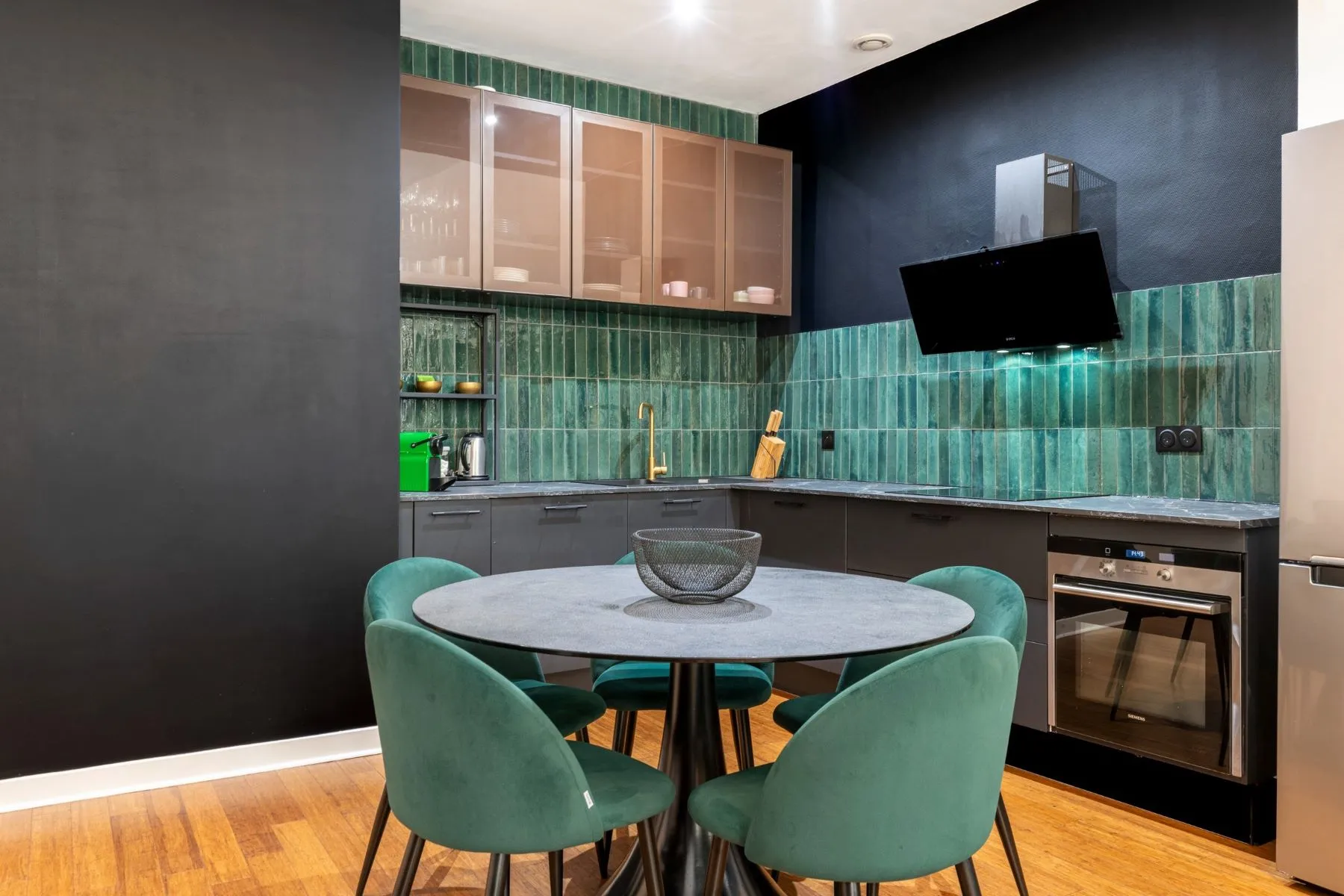 Contemporary kitchen with green glazed tiles, built-in oven and round dining table