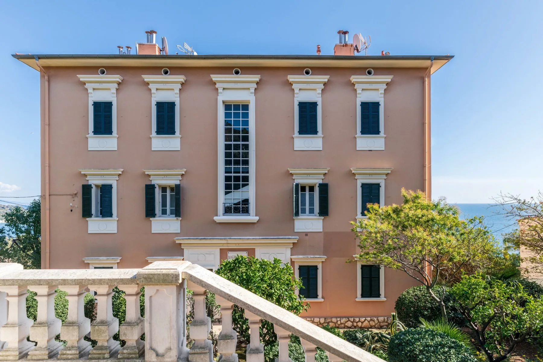 Pink Belle Époque residential façade with shutters, decorative window surrounds and stone balustrade