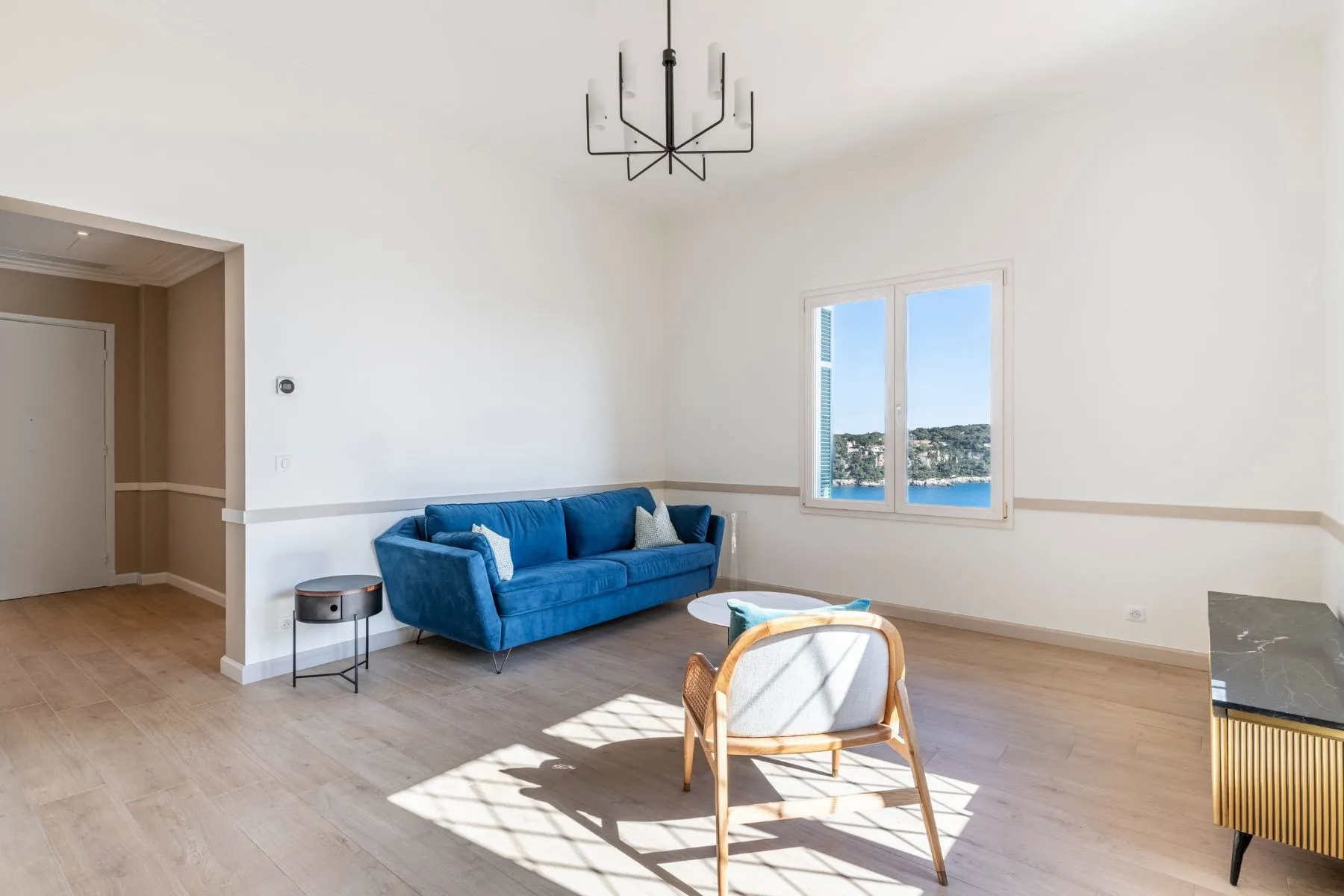 Spacious renovated living room with pale wood-toned flooring and open sea outlook