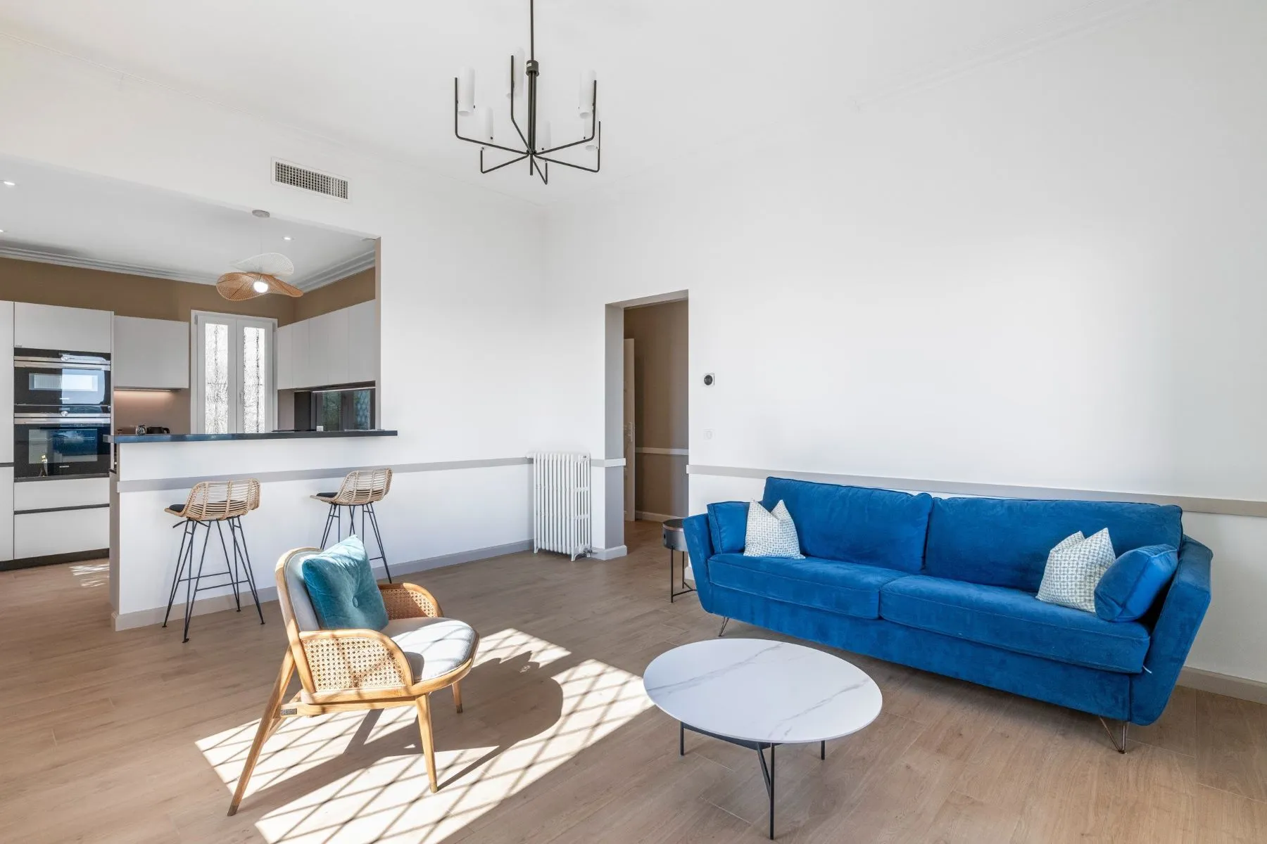 Blue-sofa lounge opening into a contemporary kitchen with breakfast counter and bar stools