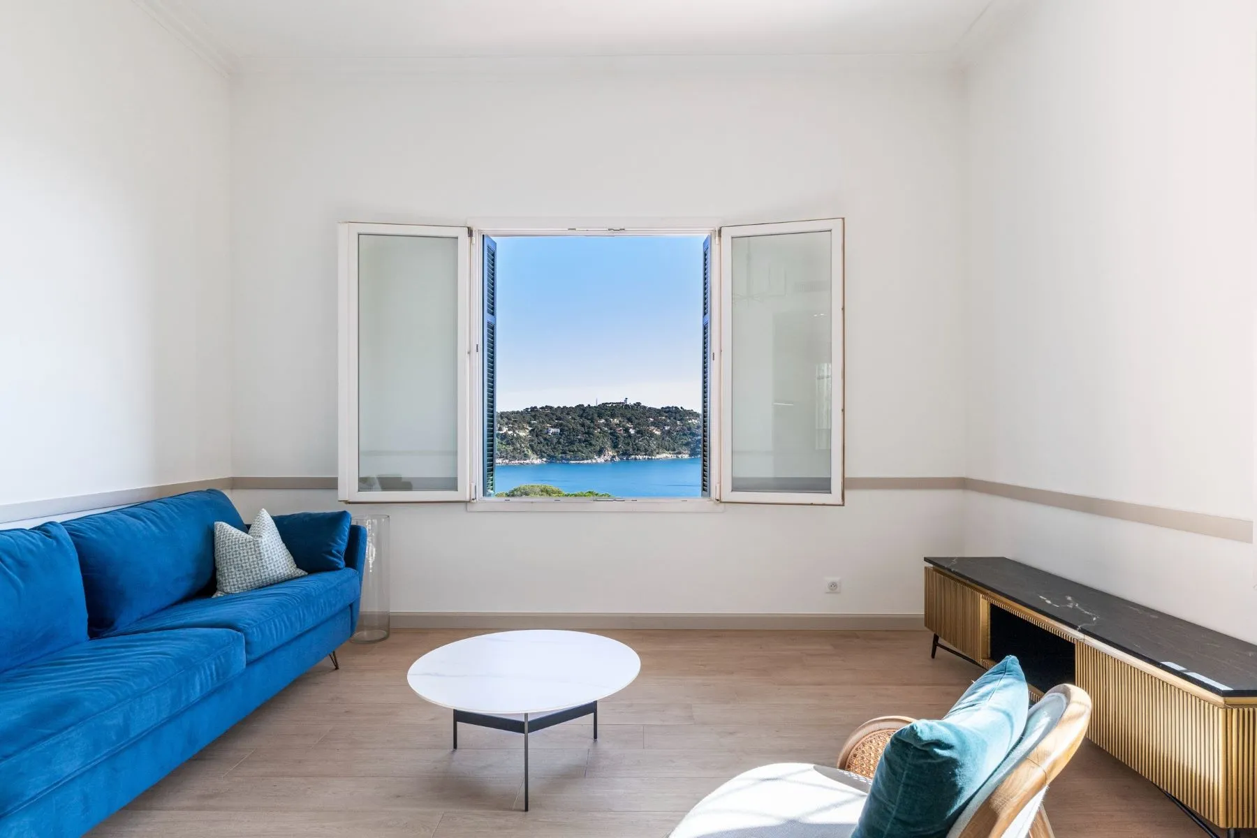 Open living-room window framing the blue Mediterranean and Saint-Jean-Cap-Ferrat coastline