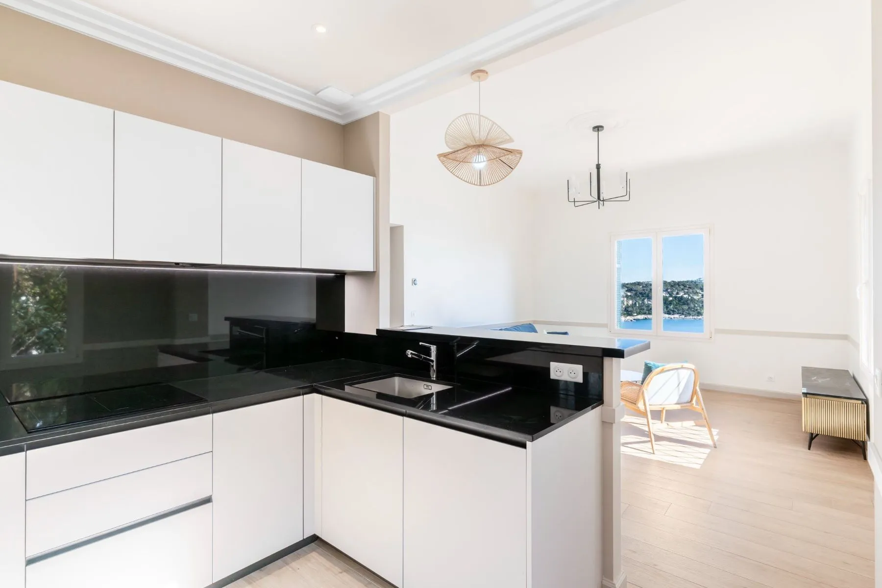 Open-plan kitchen with glossy black splashback and breakfast counter overlooking the lounge