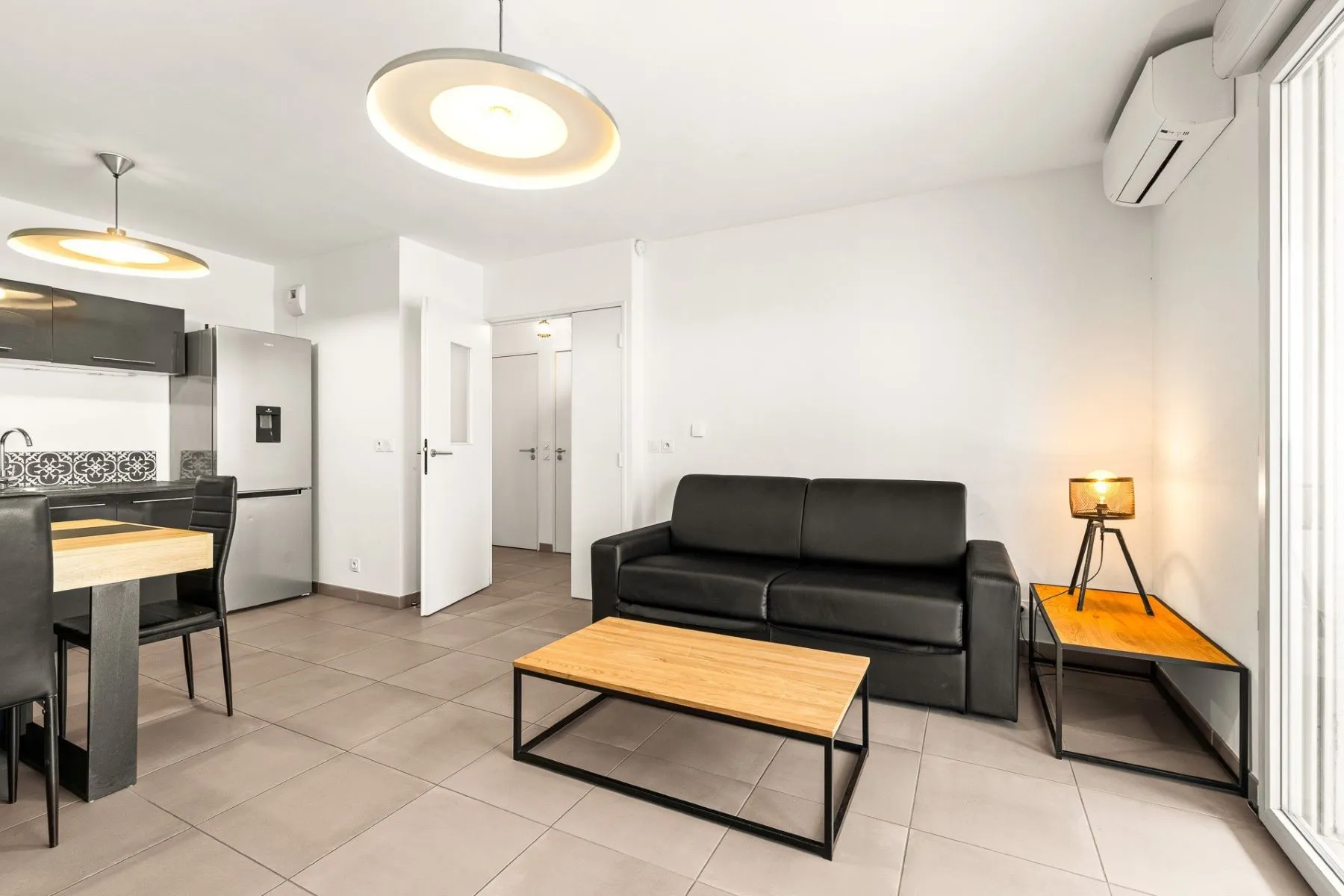 Comfortable lounge with black sofa, timber coffee table and wall-mounted air-conditioning unit
