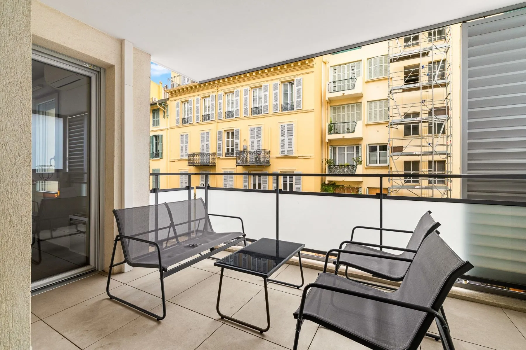 Sheltered private terrace with outdoor sofa and chairs overlooking colourful Nice façades