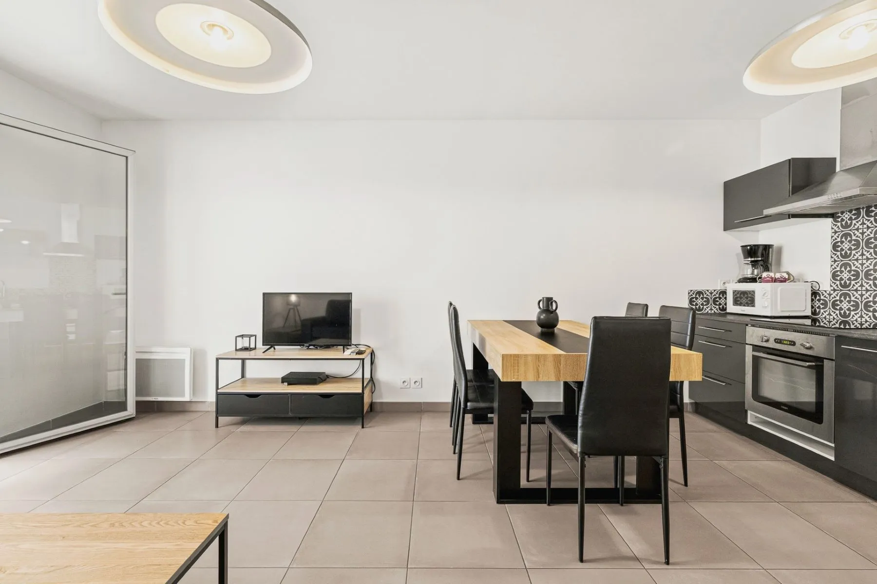 Kitchen and dining space with timber table, black chairs and living-room television