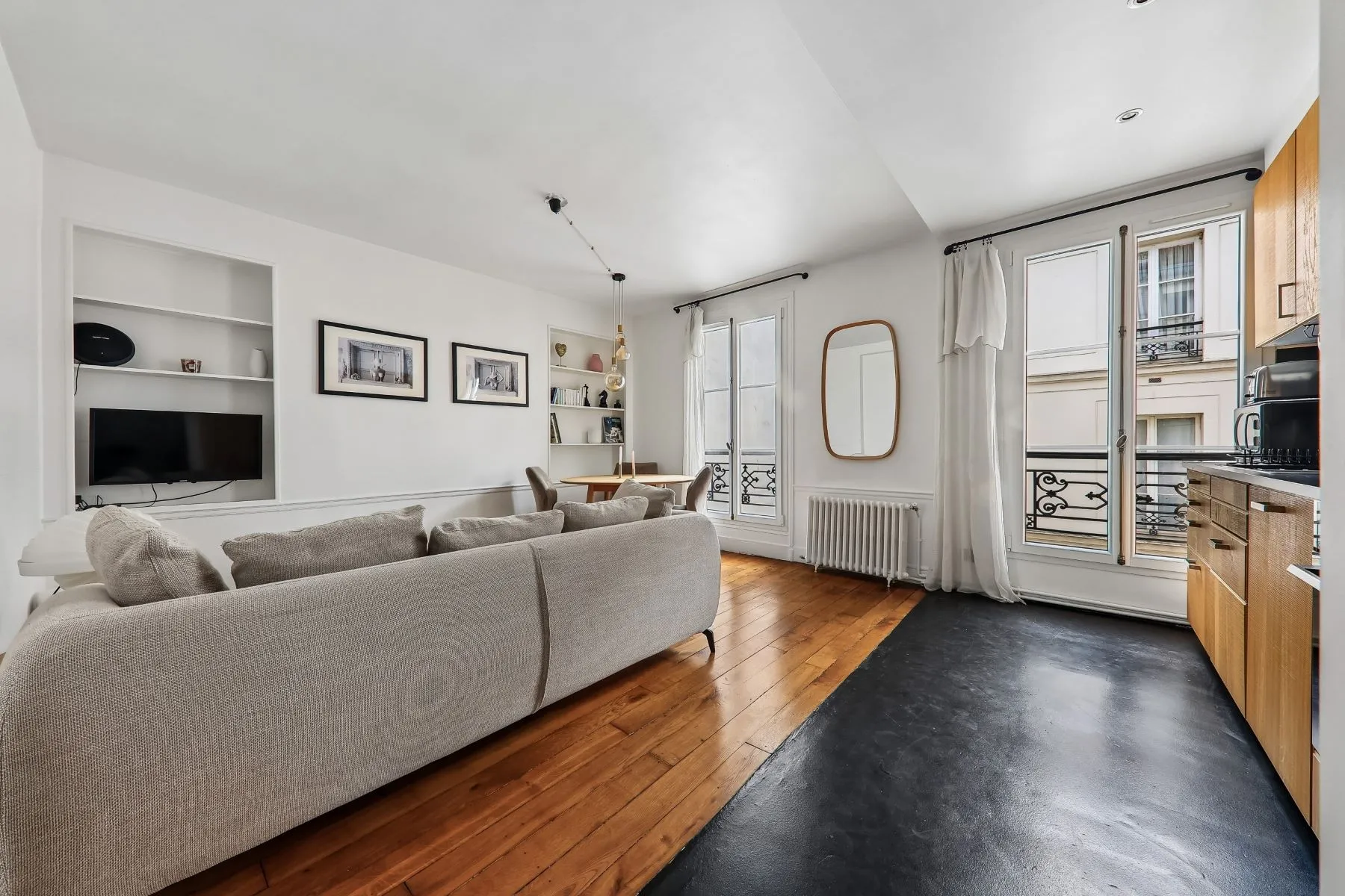 Bright Marais living room with curved cream sofa, timber floors and tall windows