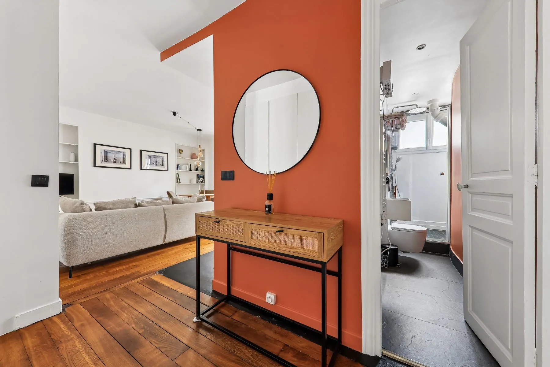 Entrance area with terracotta-coloured wall, round mirror and timber console