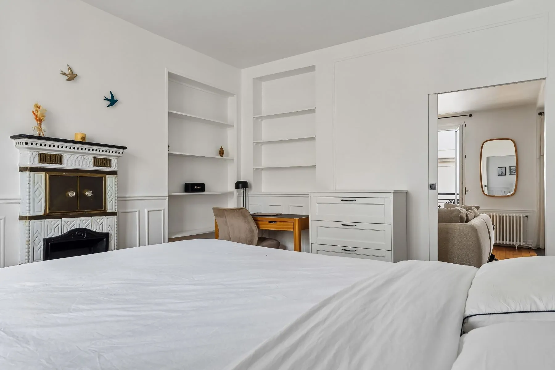 First bedroom with decorative fireplace, built-in shelving and a compact desk