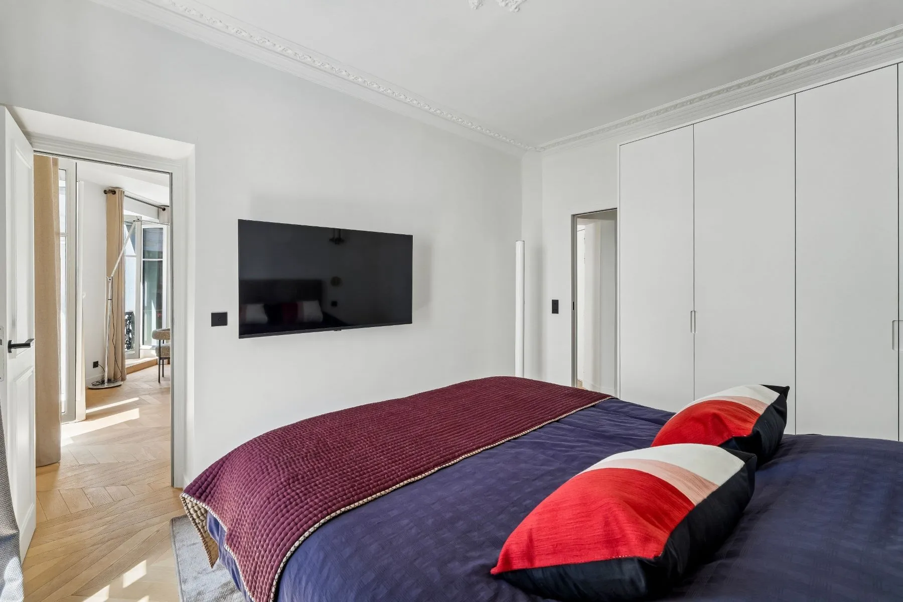 Second double bedroom with wall-mounted television and doorway into the bright living room