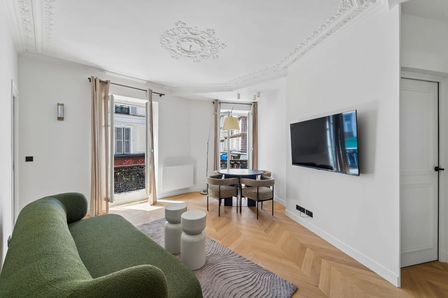 Living room with wall-mounted television and street-facing windows with decorative iron railings