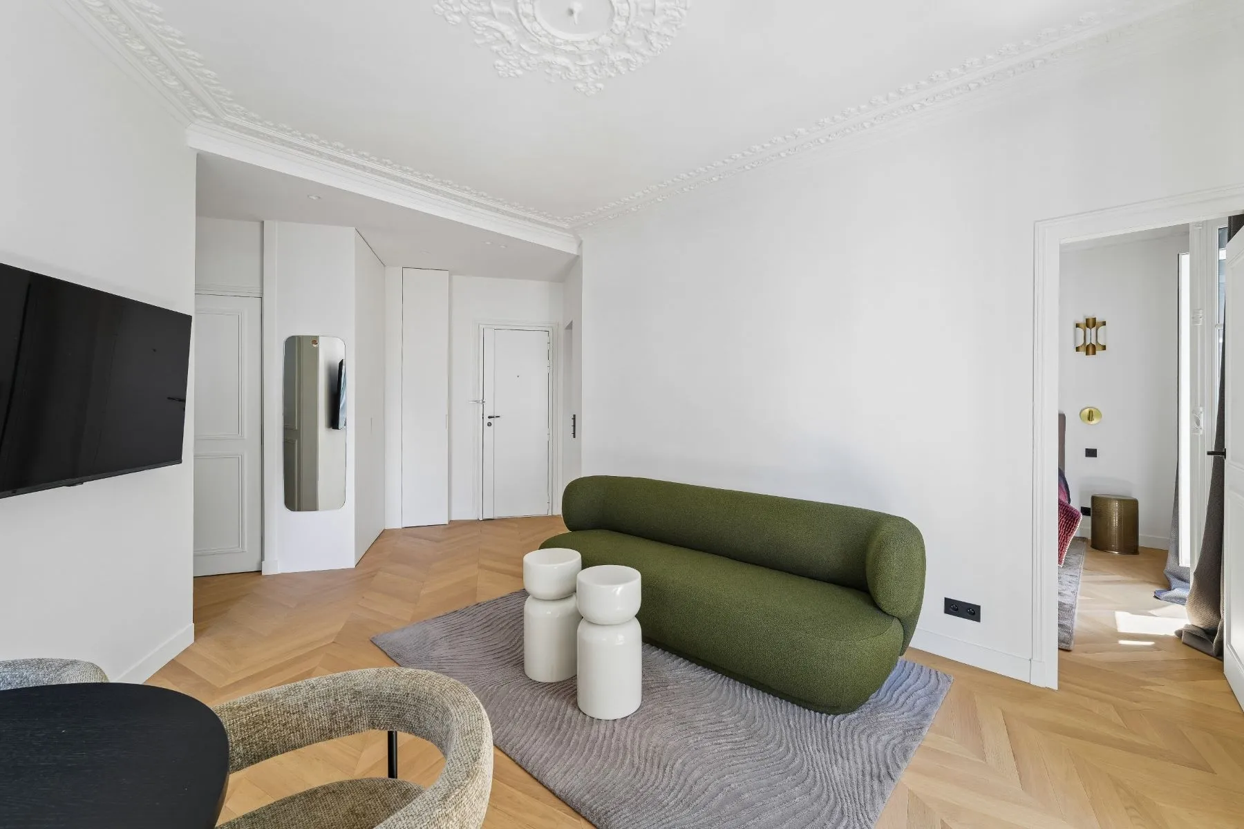 Renovated lounge with decorative ceiling rose, green sofa and built-in hallway storage