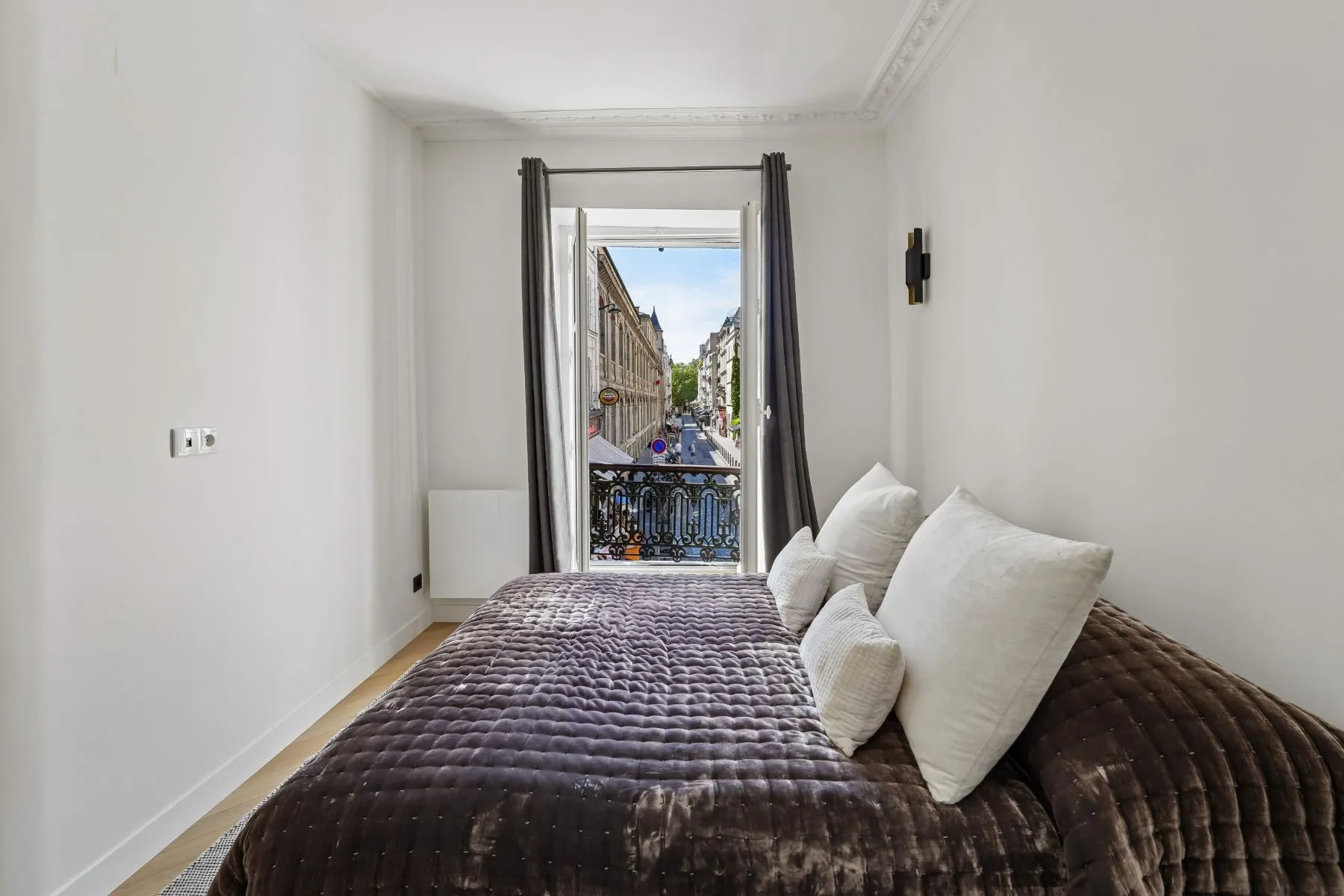 First double bedroom with textured brown bedspread and view along a Montmartre street