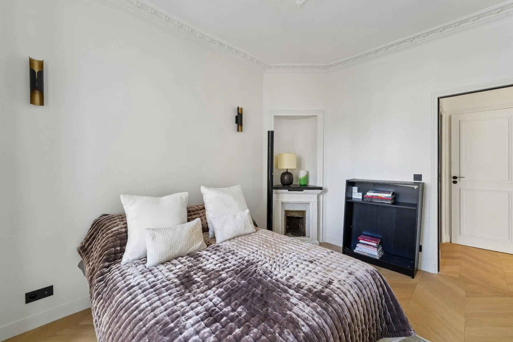 Double bedroom viewed toward the decorative fireplace, bookcase and timber parquet floor