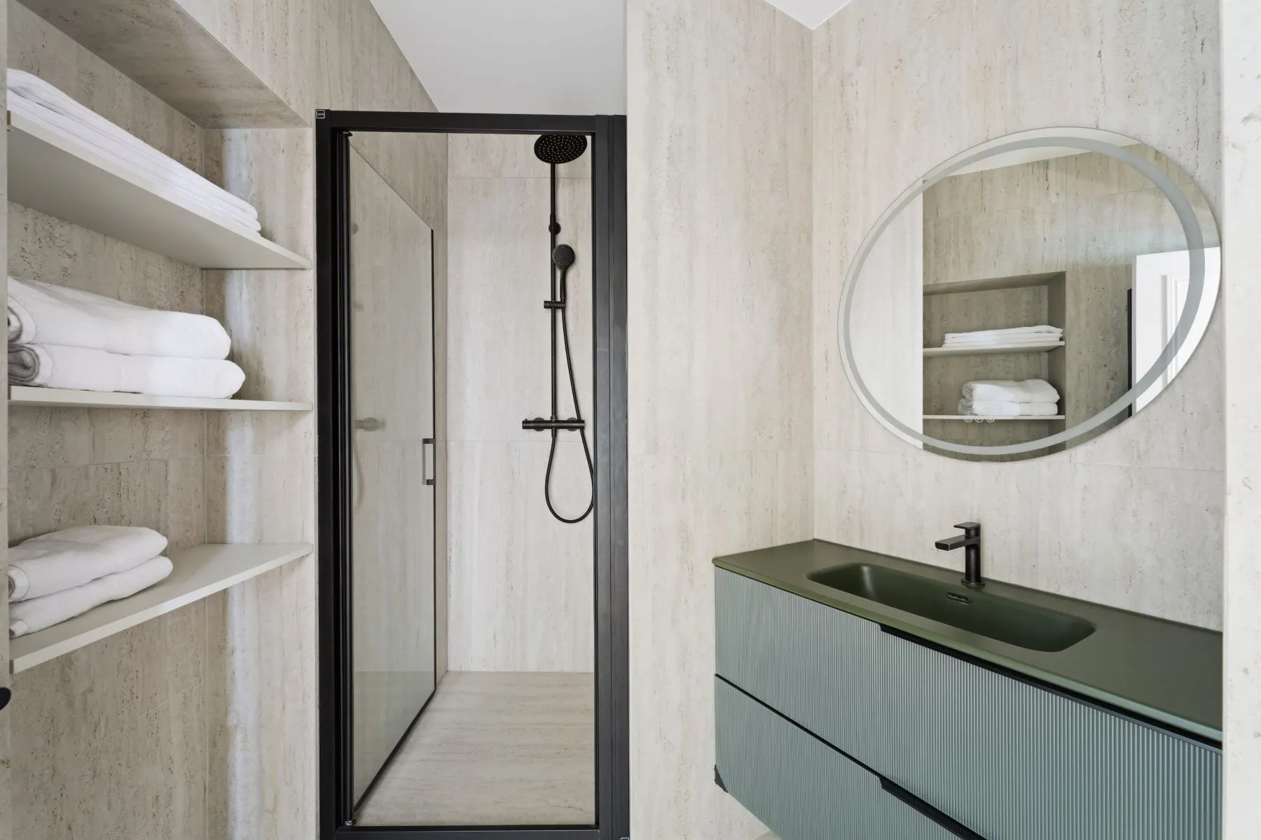 Contemporary shower room with glass enclosure, black fittings and green vanity beneath a round mirror