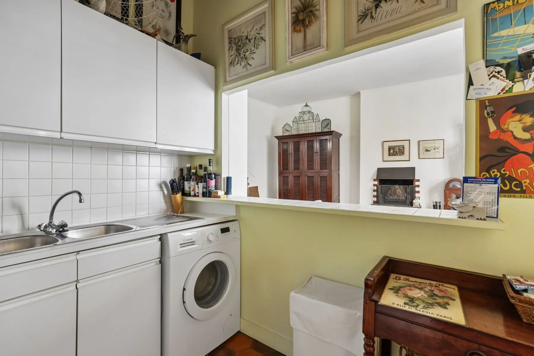 Compact open kitchen with white cabinetry washing machine and breakfast counter