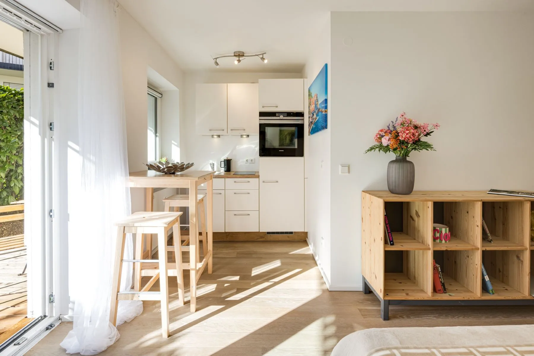 Compact white fitted kitchen with breakfast counter beside the terrace doors