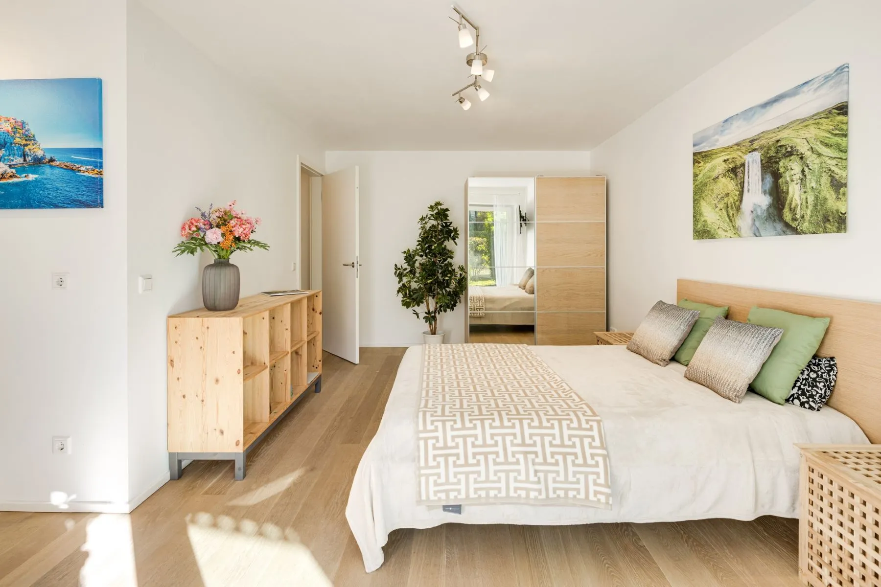 Open-plan studio with timber bed, open shelving and mirrored wardrobe