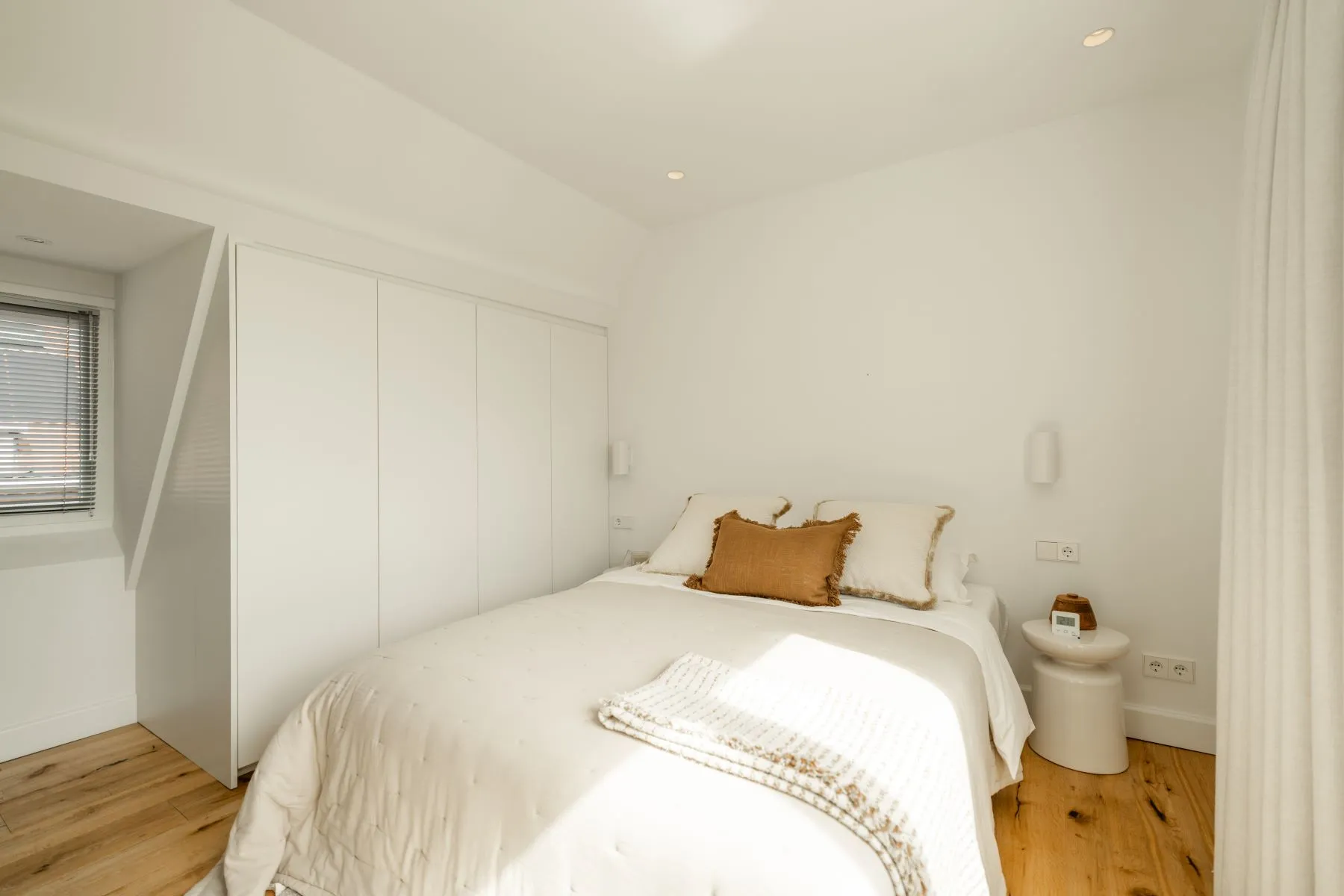 Calm private bedroom with fitted white wardrobes and reading light
