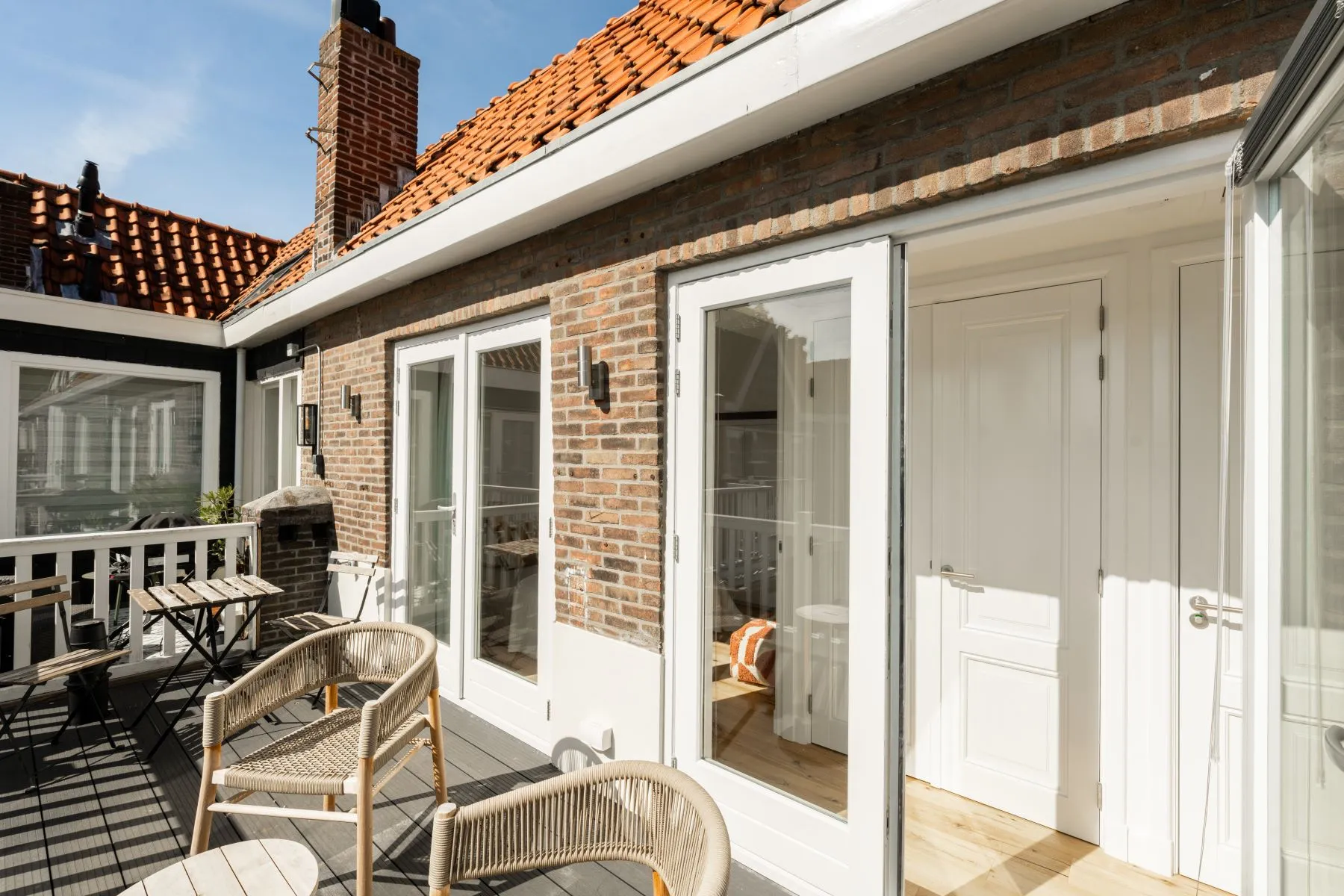 Sunny upper terrace outside the white timber maisonette façade