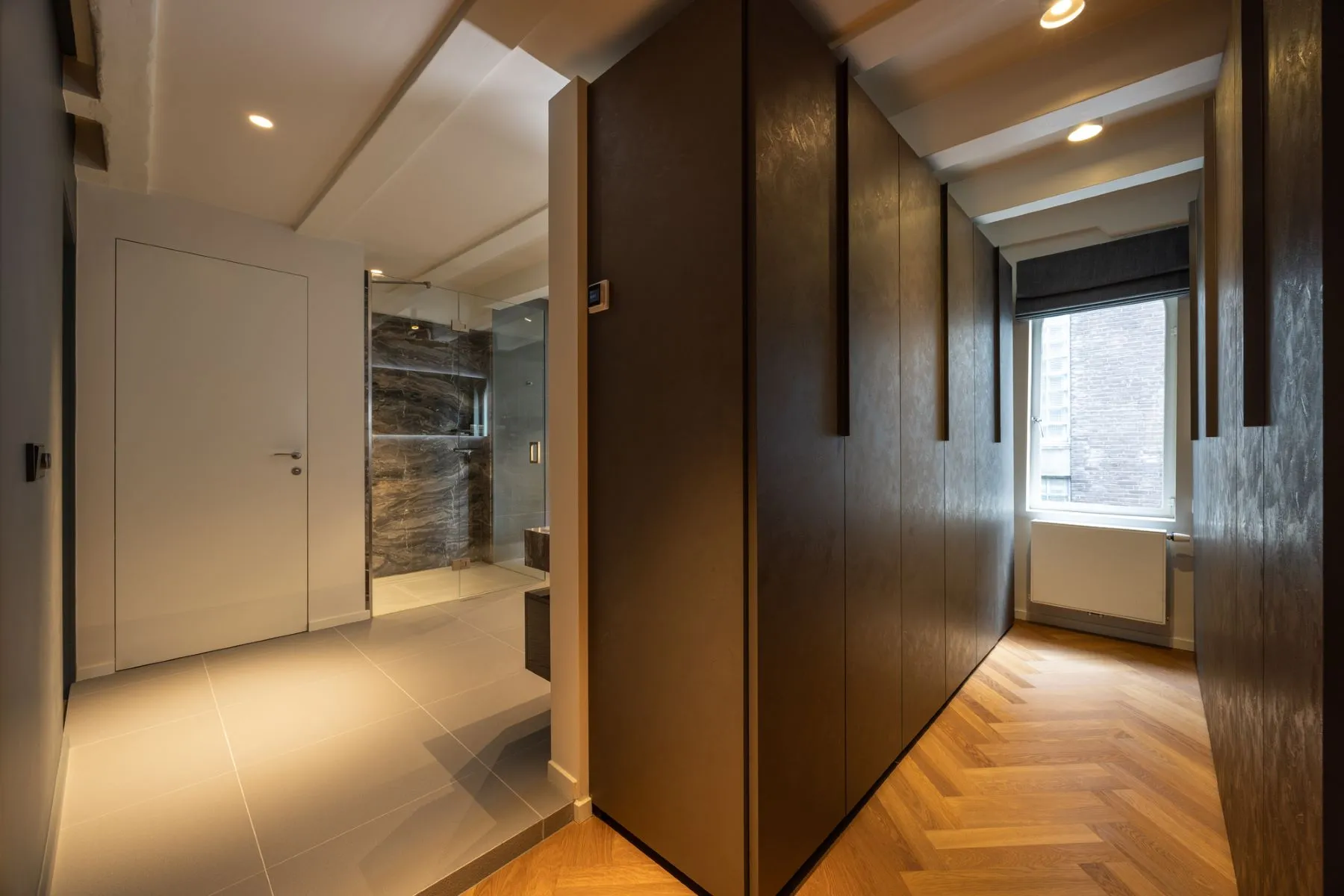 Principal-suite dressing hall with extensive dark timber wardrobes