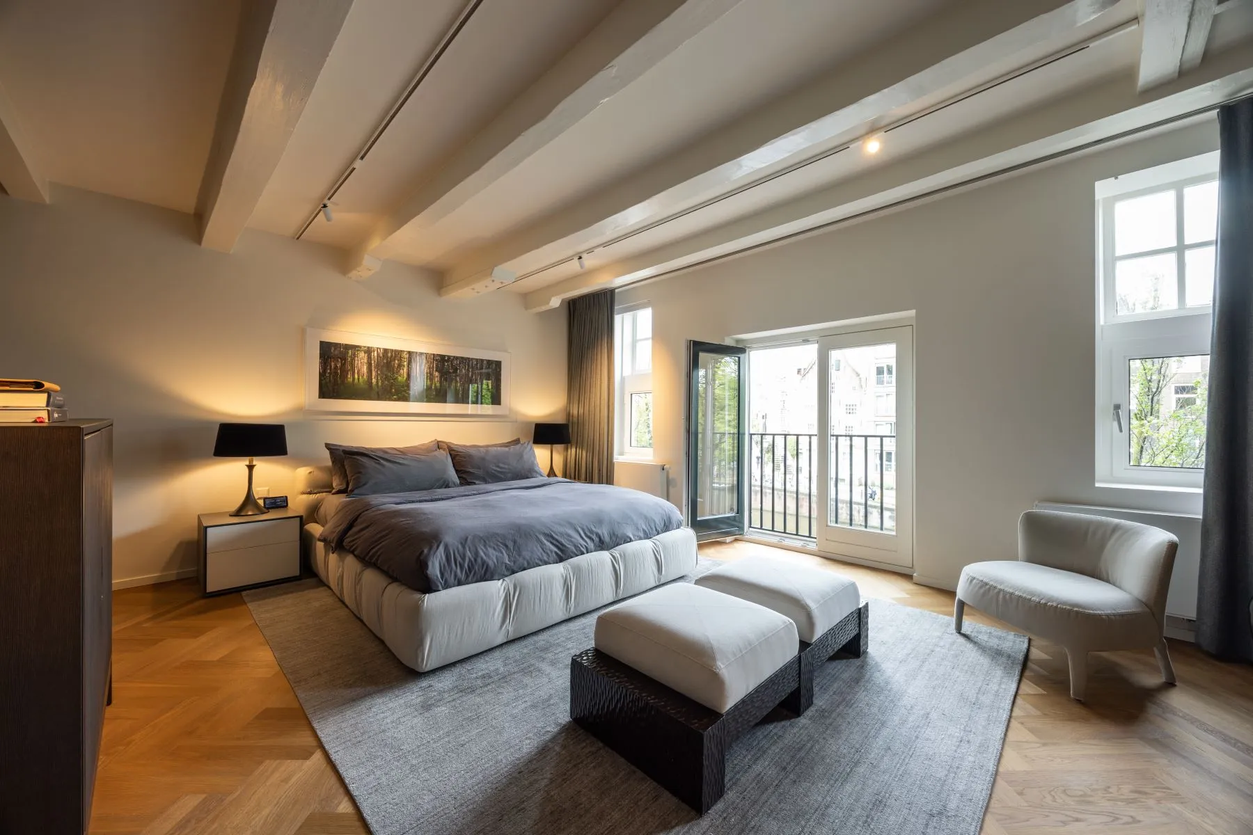 Generous principal suite with upholstered bed and reading chair