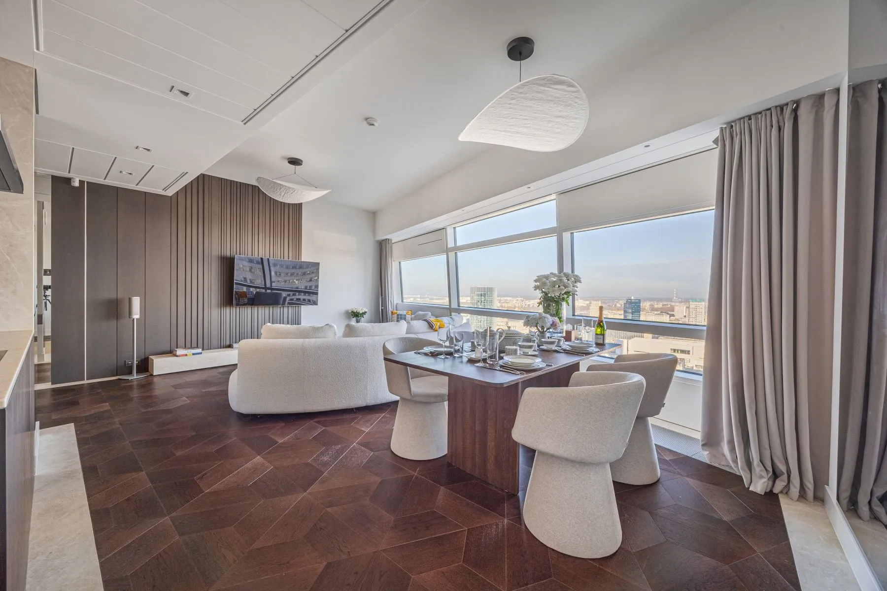 Open living and dining room with bespoke timber cabinetry and wide Warsaw skyline views