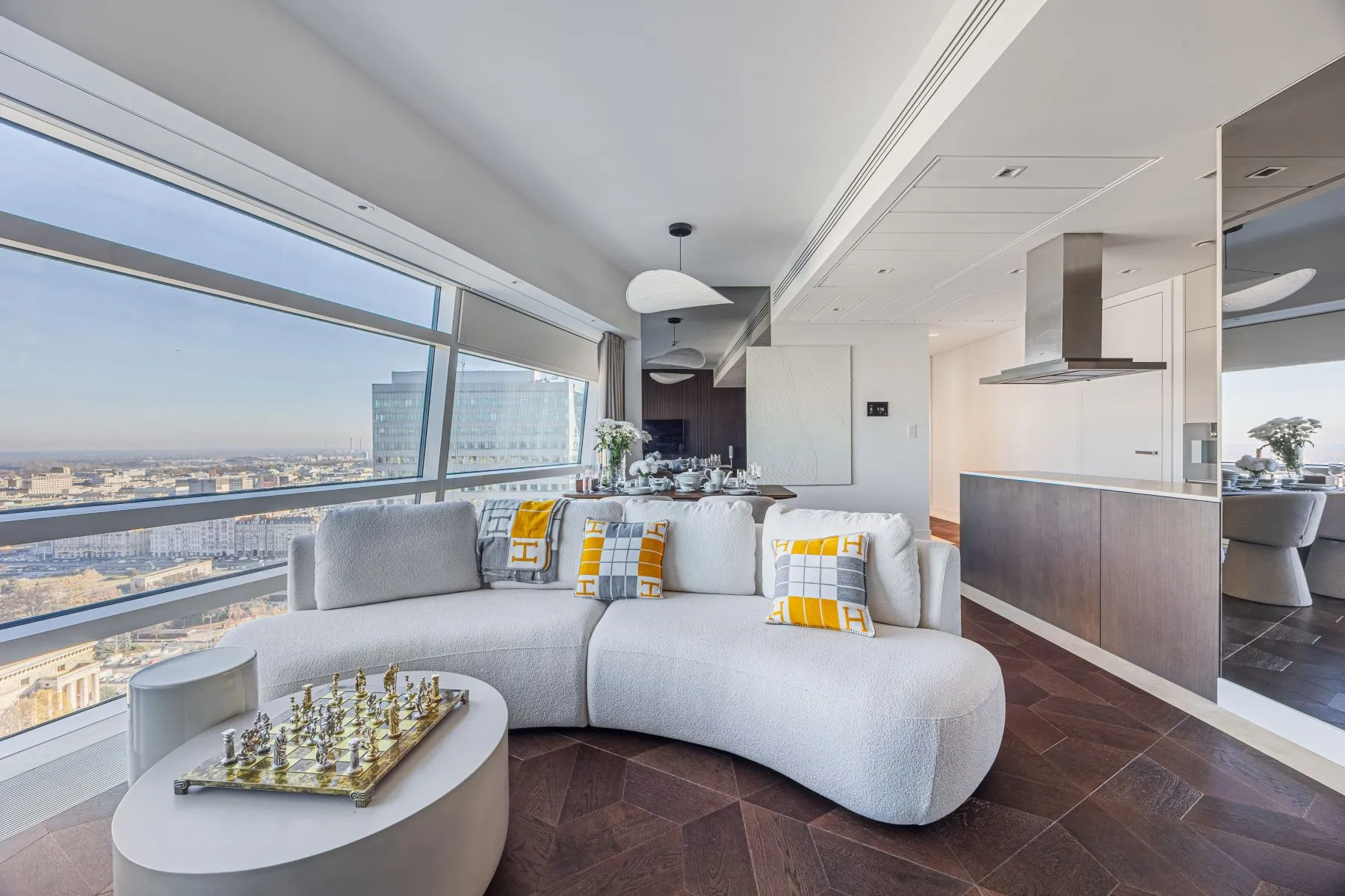 Sculptural lounge seating beside wraparound city-facing windows and the open kitchen
