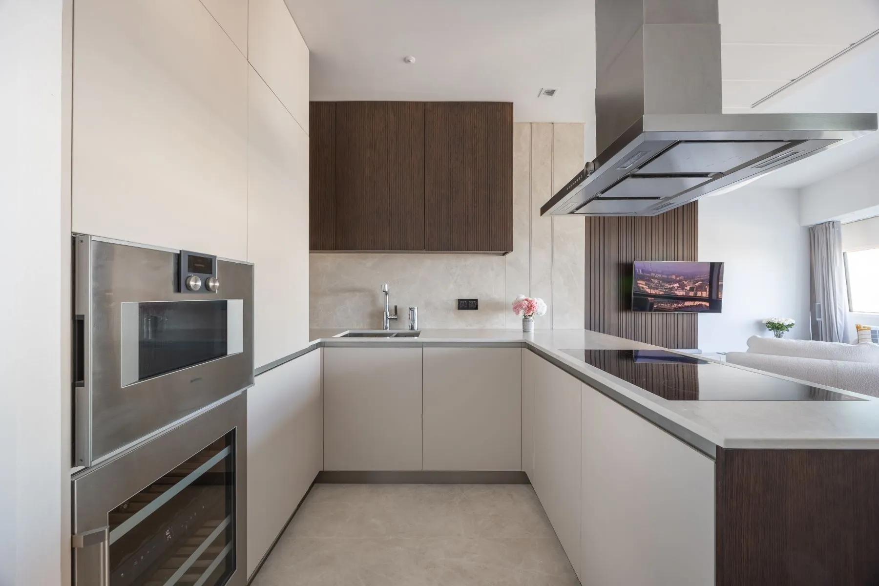Contemporary fitted kitchen with integrated ovens, island hob and overhead extractor