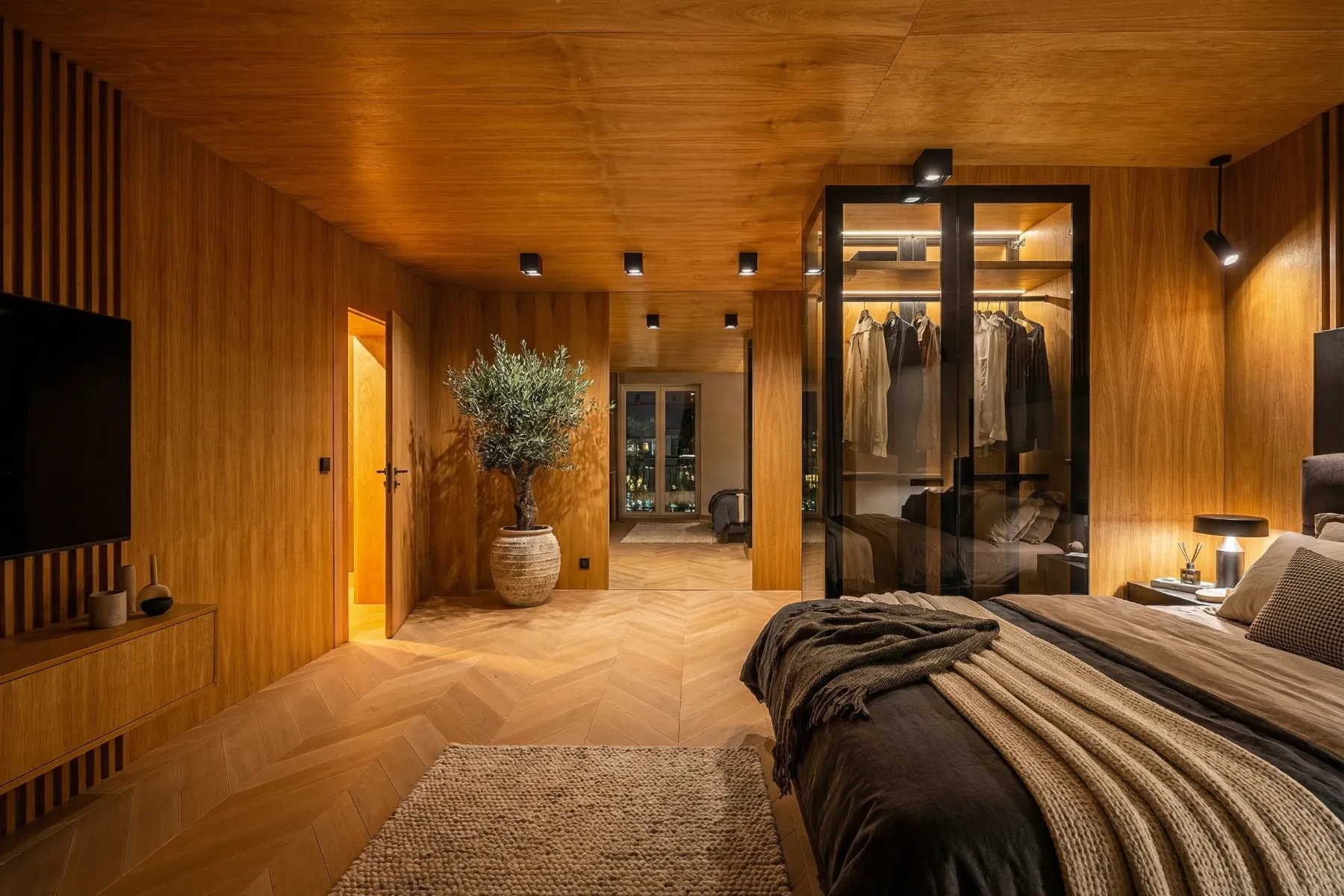 Principal double bedroom with timber finishes, glass-fronted wardrobe and television