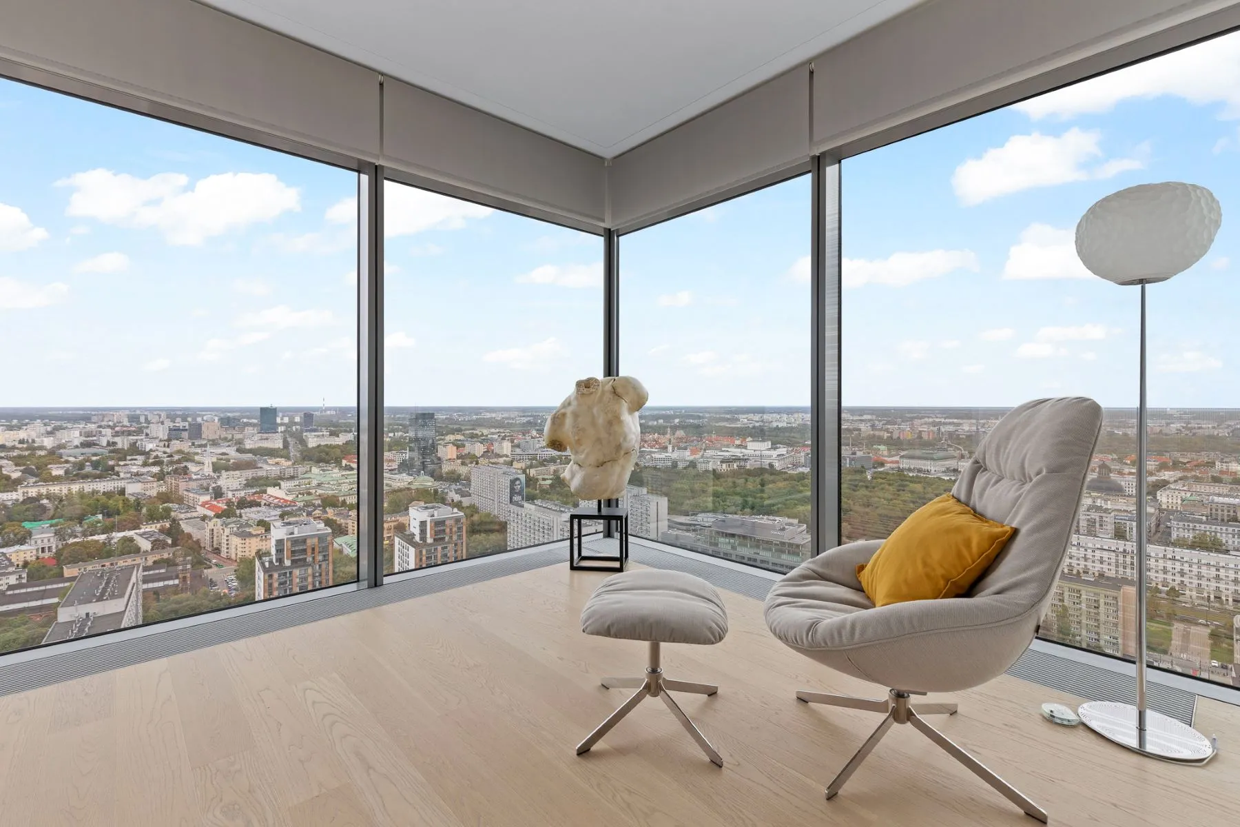 Corner lounge at Cosmopolitan Tower with a grey armchair, footstool and panoramic Warsaw views