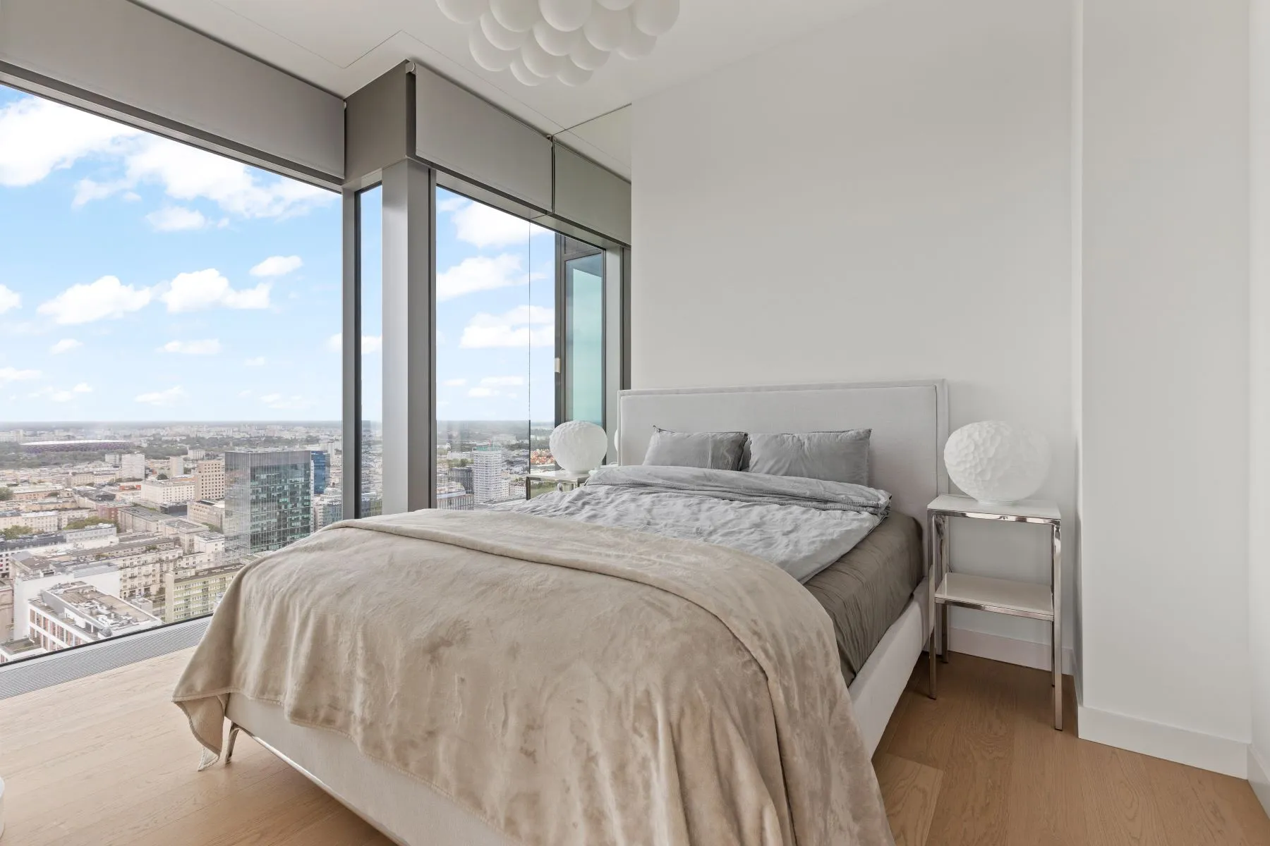 Double bedroom with a grey upholstered headboard, bedside tables and expansive skyline views