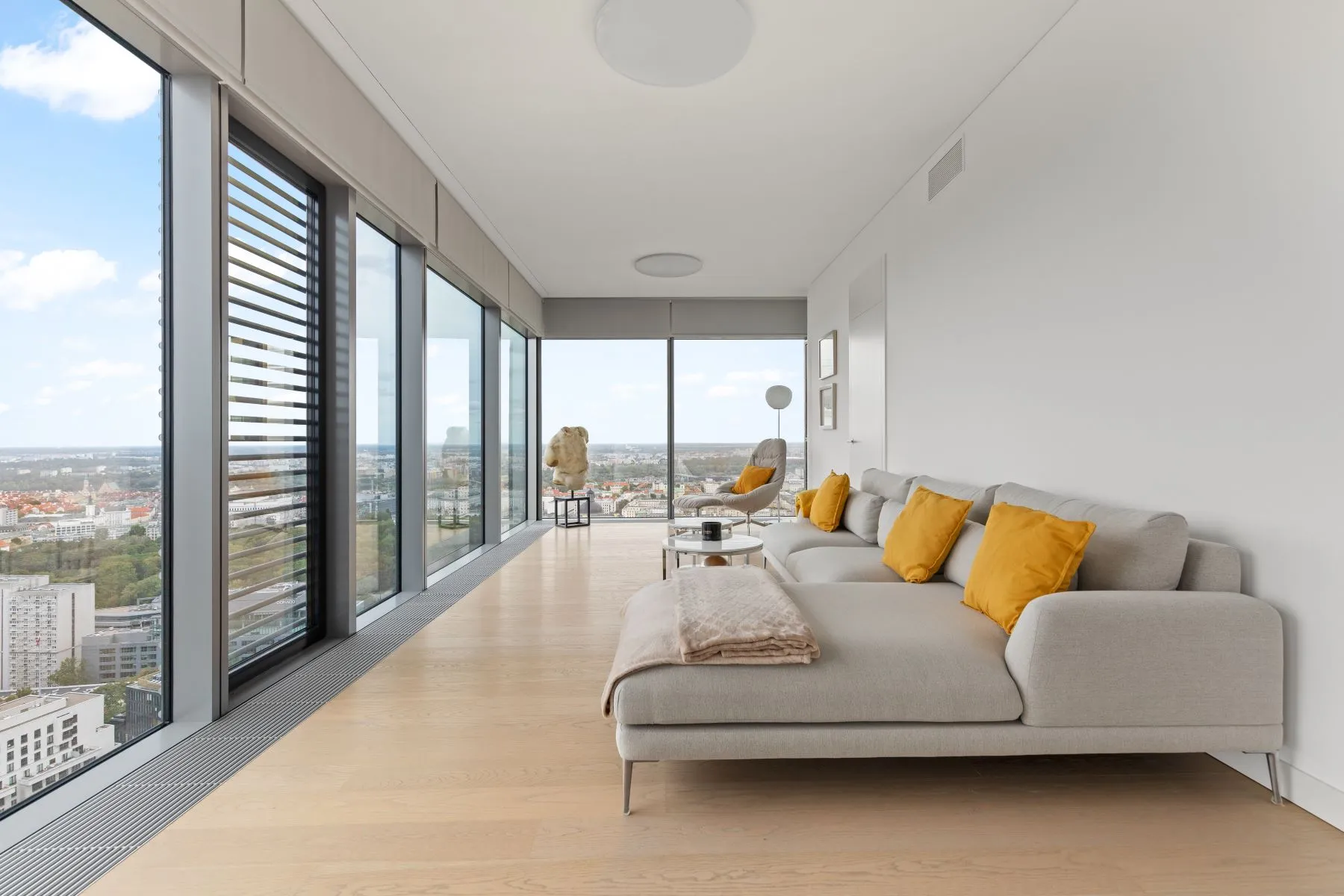 Long open-plan living room with a chaise sofa, white column and pale timber floor