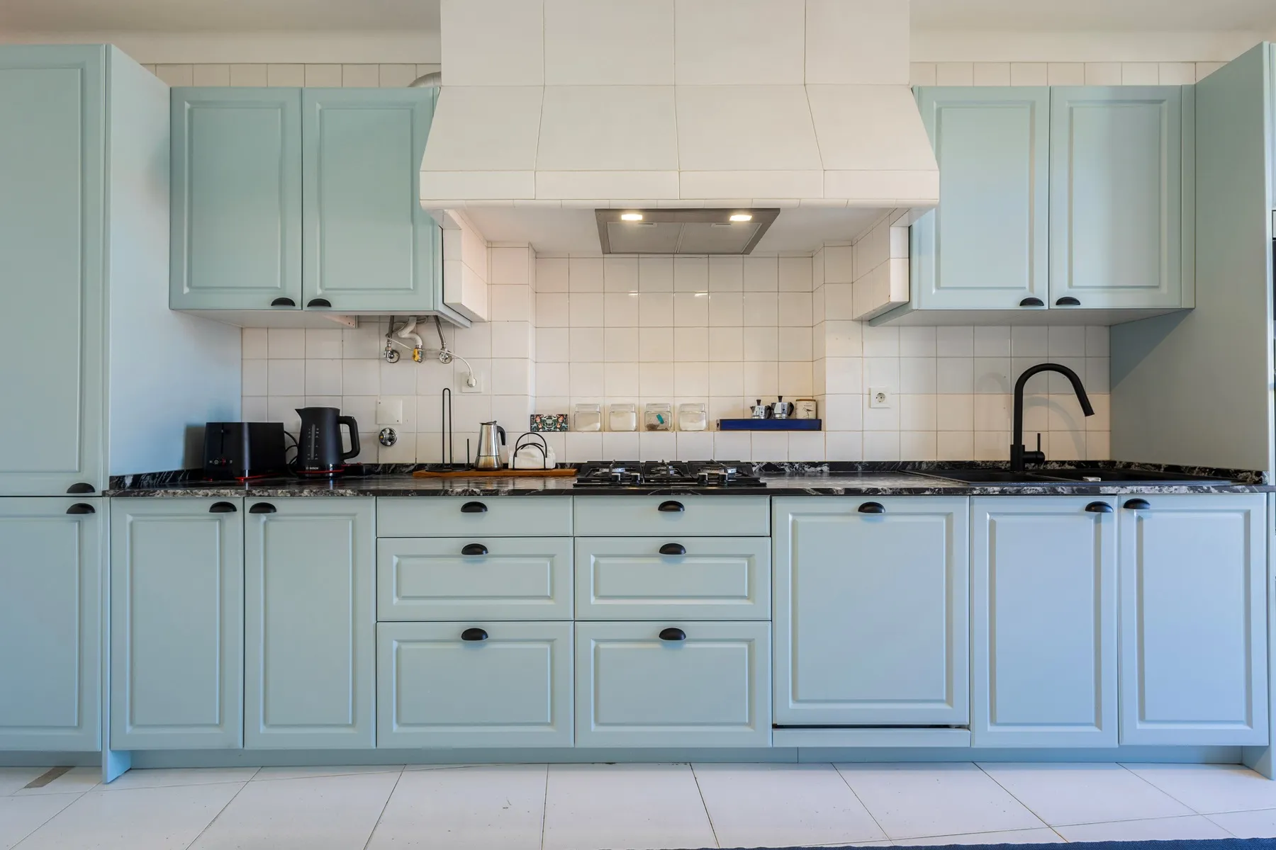 Traditional pale blue kitchen with integrated appliances and marble worktop