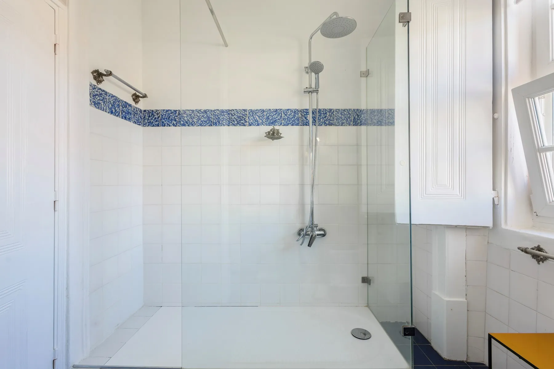 Glass-enclosed walk-in shower with blue mosaic accent tile