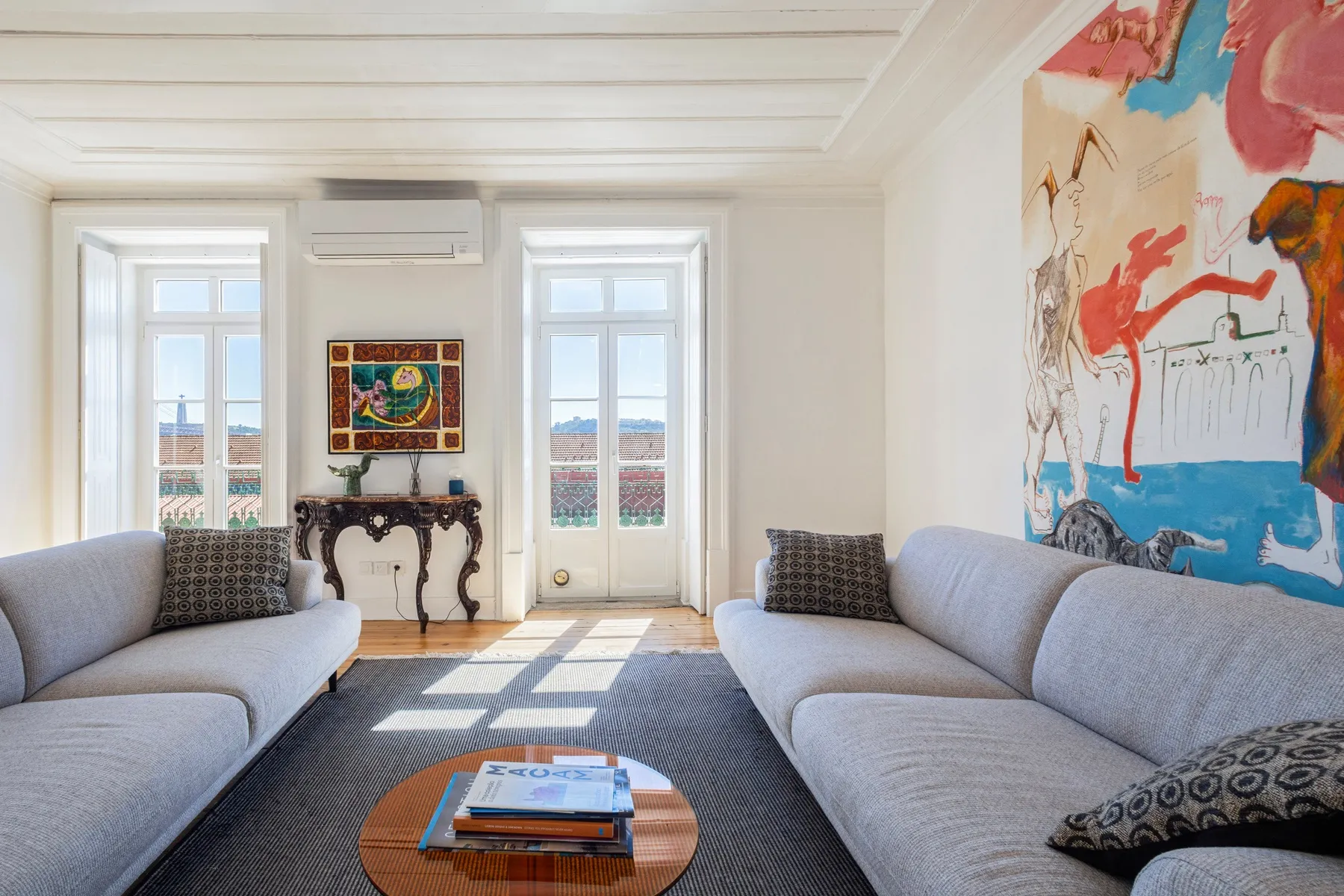 Art-filled living room with broad windows and generous sofa seating
