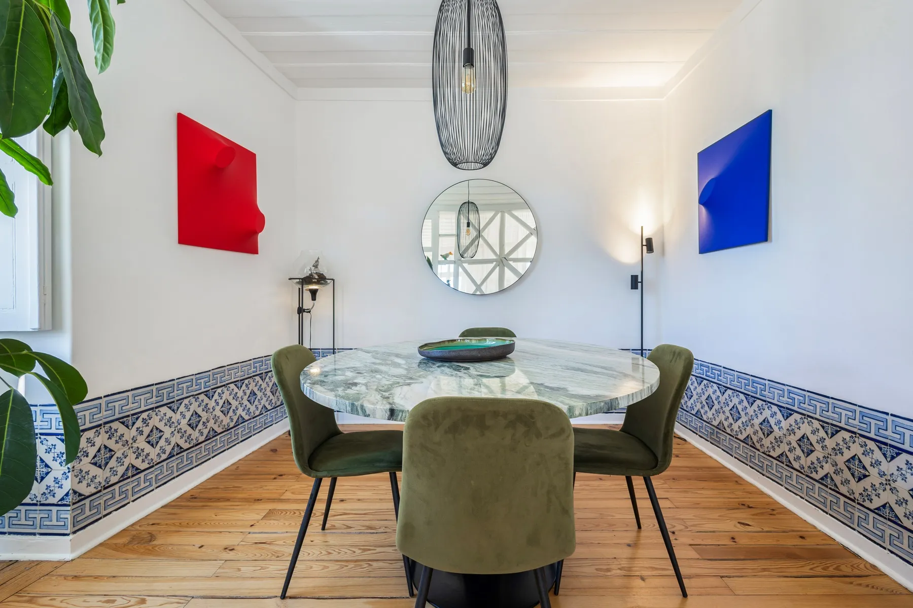 Formal dining table beneath statement lighting and colourful artwork