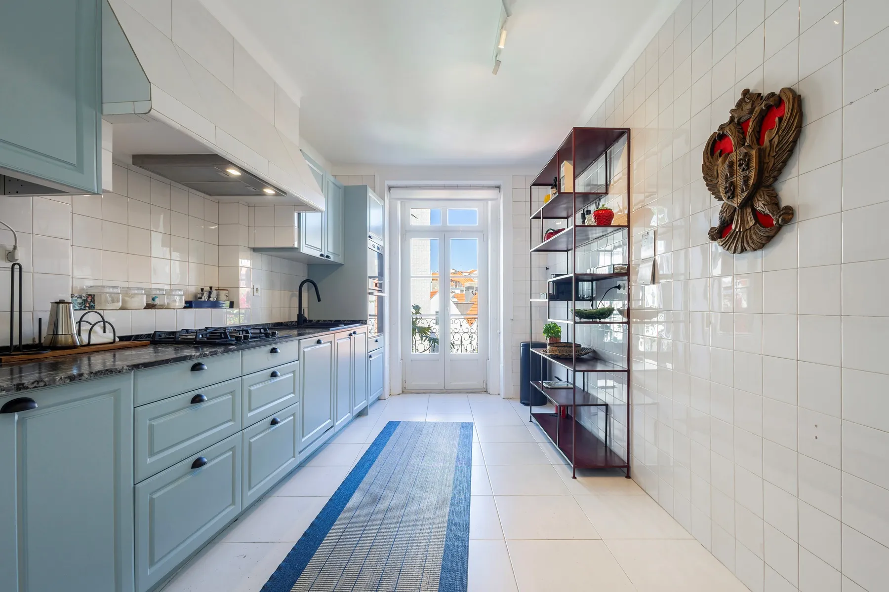 Long fitted kitchen with pale blue cabinetry and balcony doors
