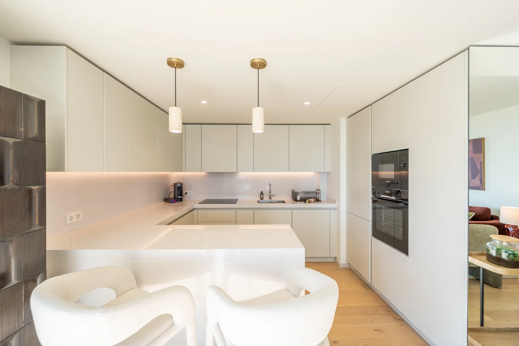 Contemporary living area viewed toward the pale fitted kitchen