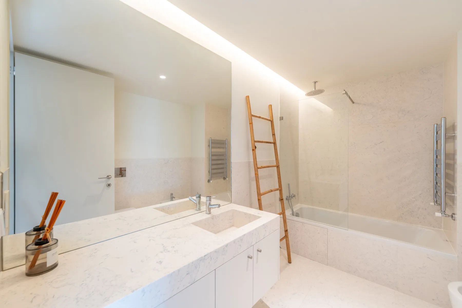 Contemporary bathroom with full bathtub and broad mirrored wall