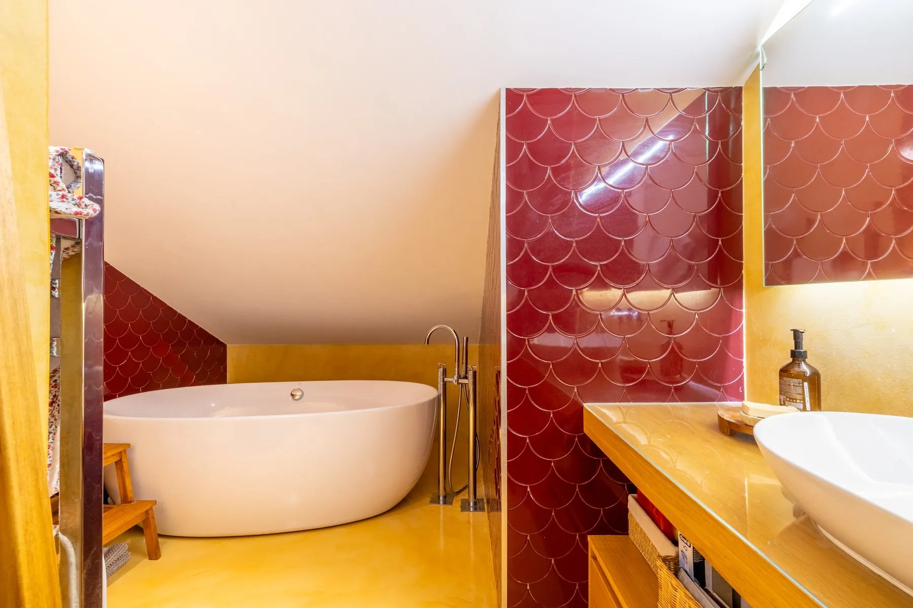 Dramatic en-suite bathroom with freestanding bathtub and red tile
