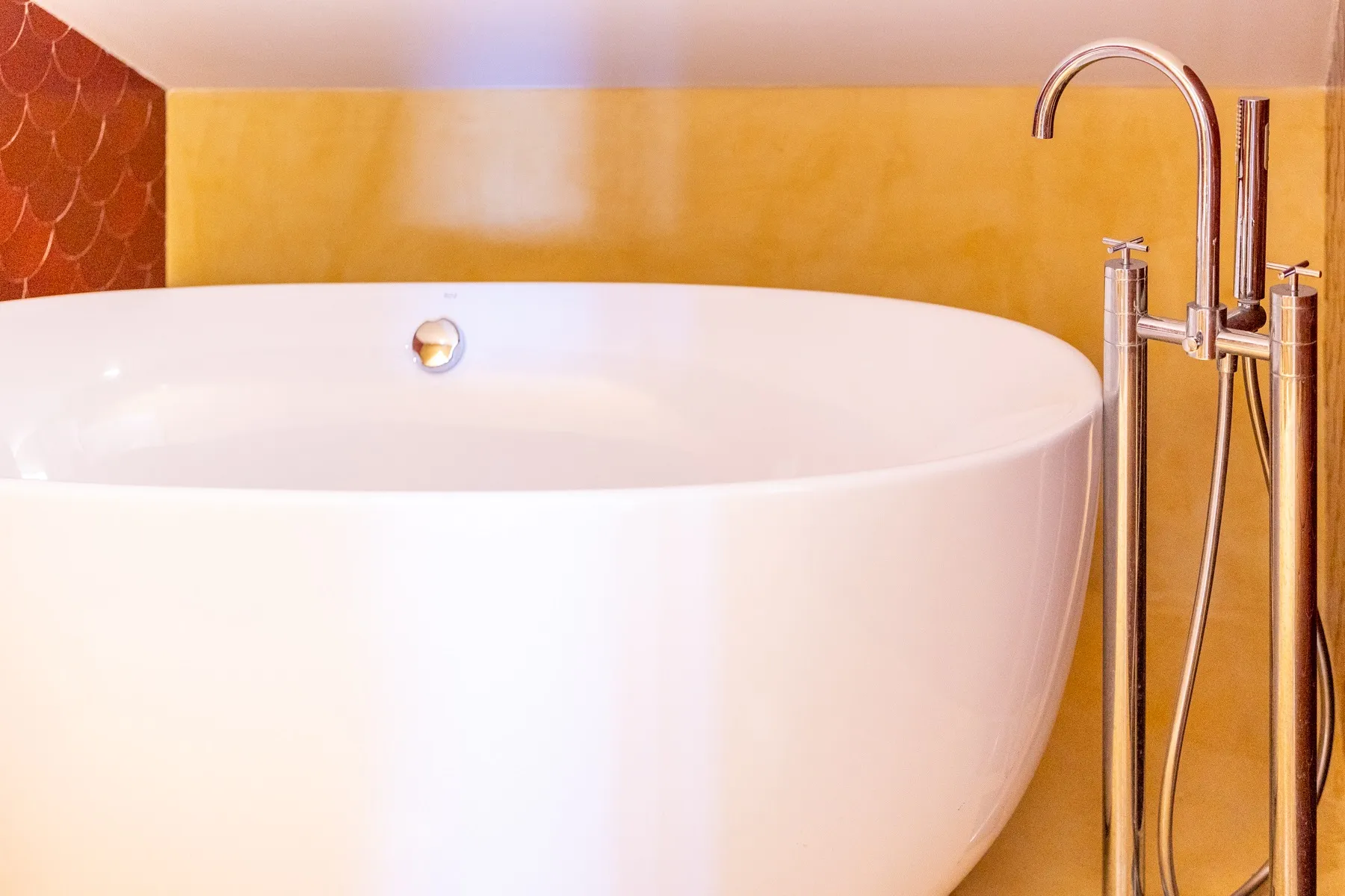 Freestanding soaking tub with handheld shower in the principal bathroom