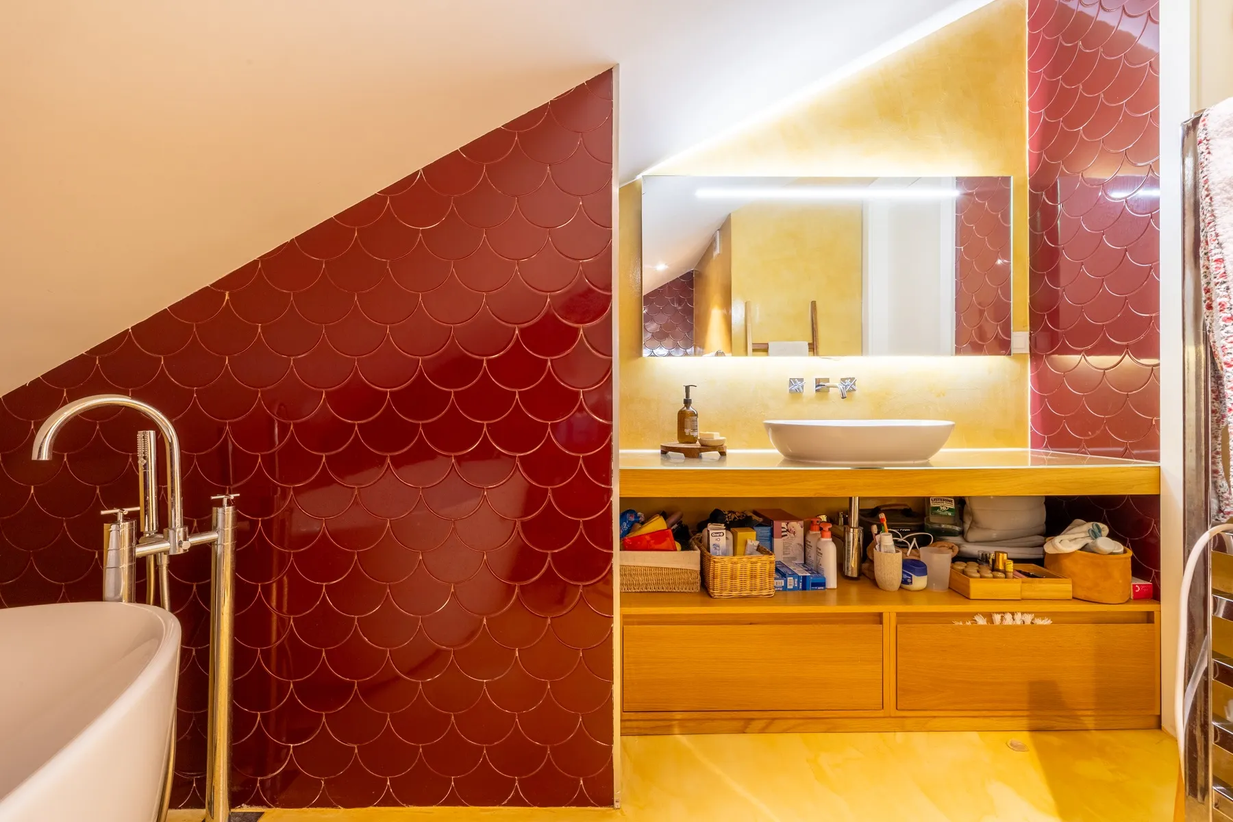 Illuminated double vanity within the red and gold en-suite bathroom