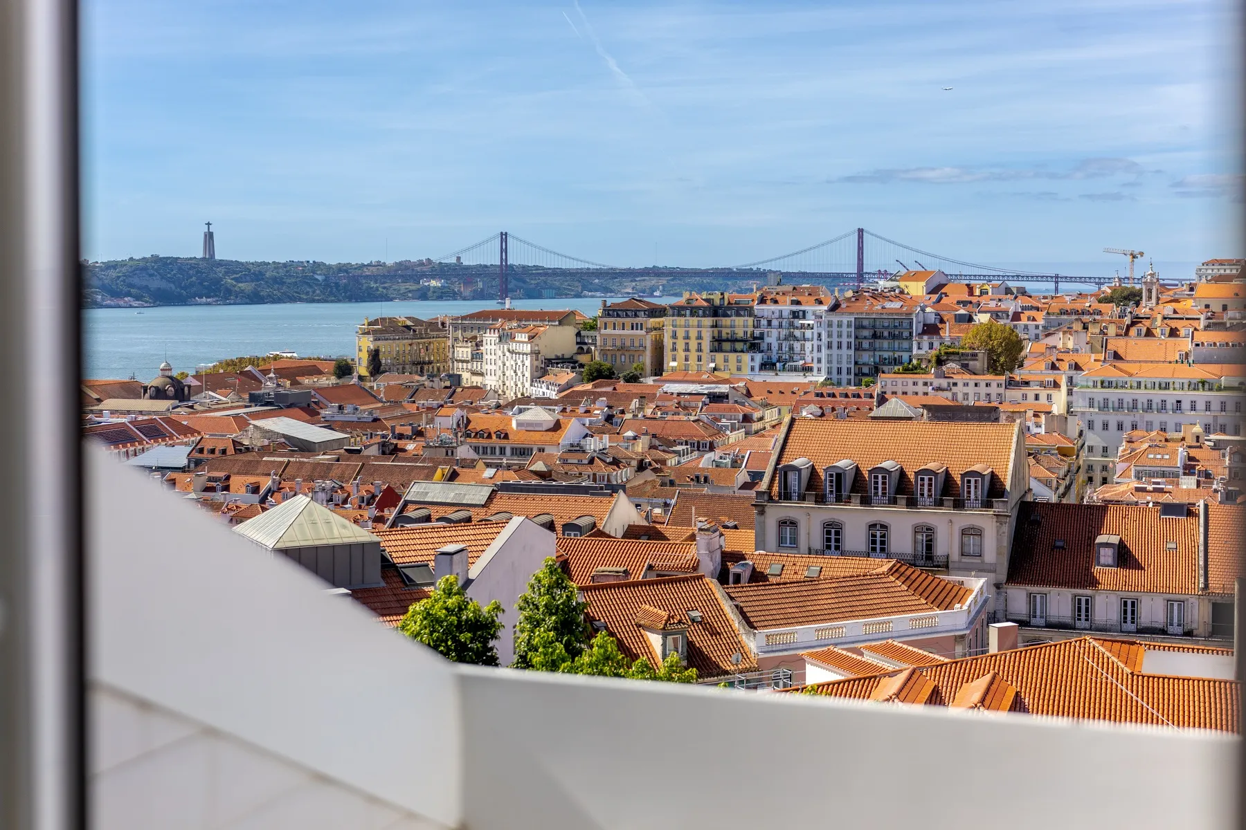 Panoramic view over Lisbon rooftops toward the Tagus and 25 de Abril Bridge