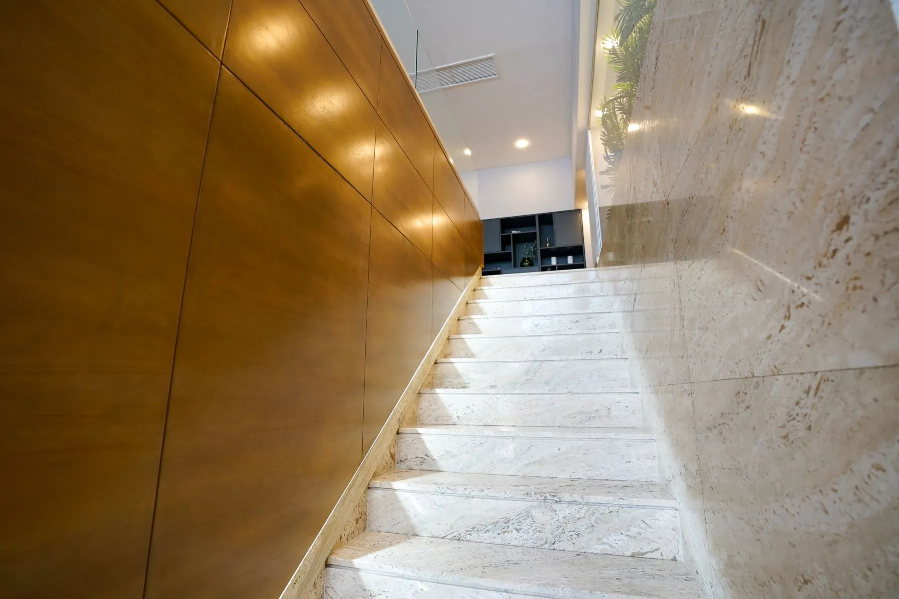 Marble staircase beside warm timber wall panels inside the Floreasca villa