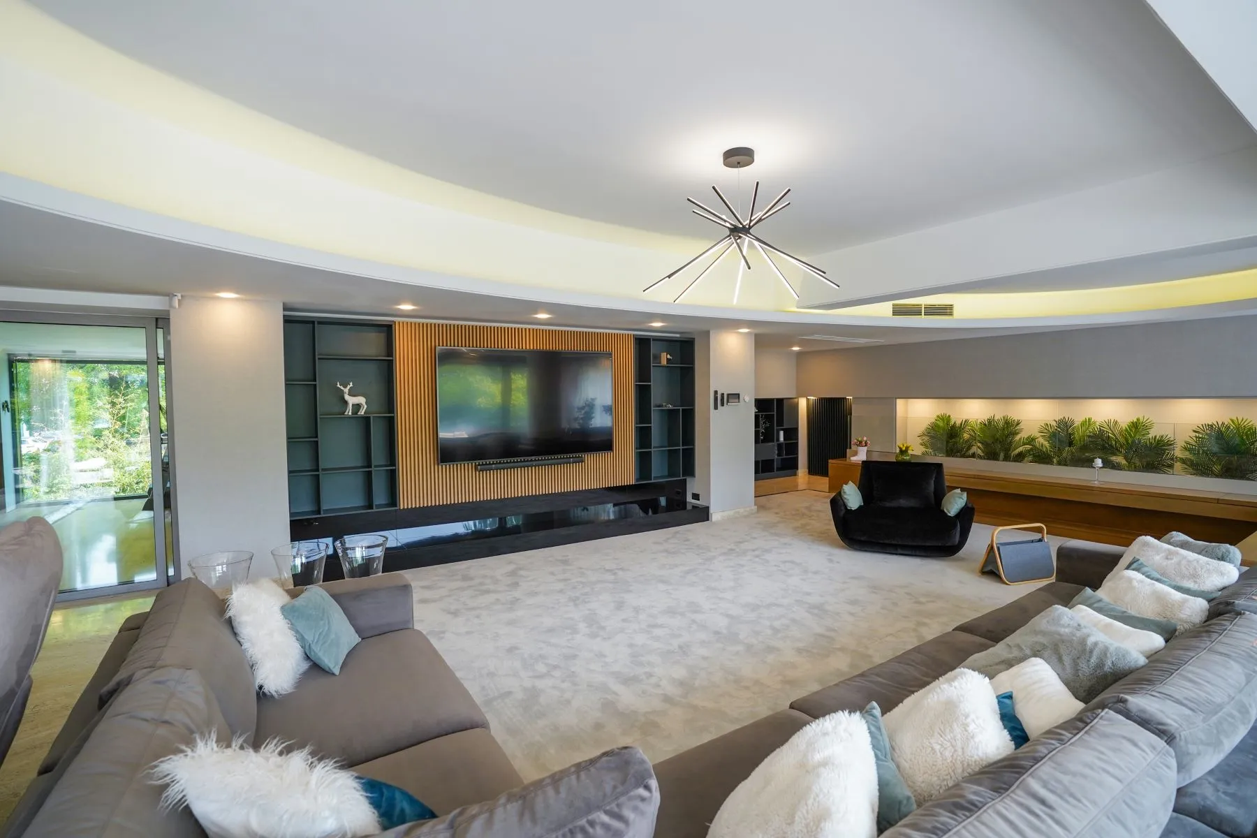 Spacious reception room with sectional sofas, television wall and garden doors