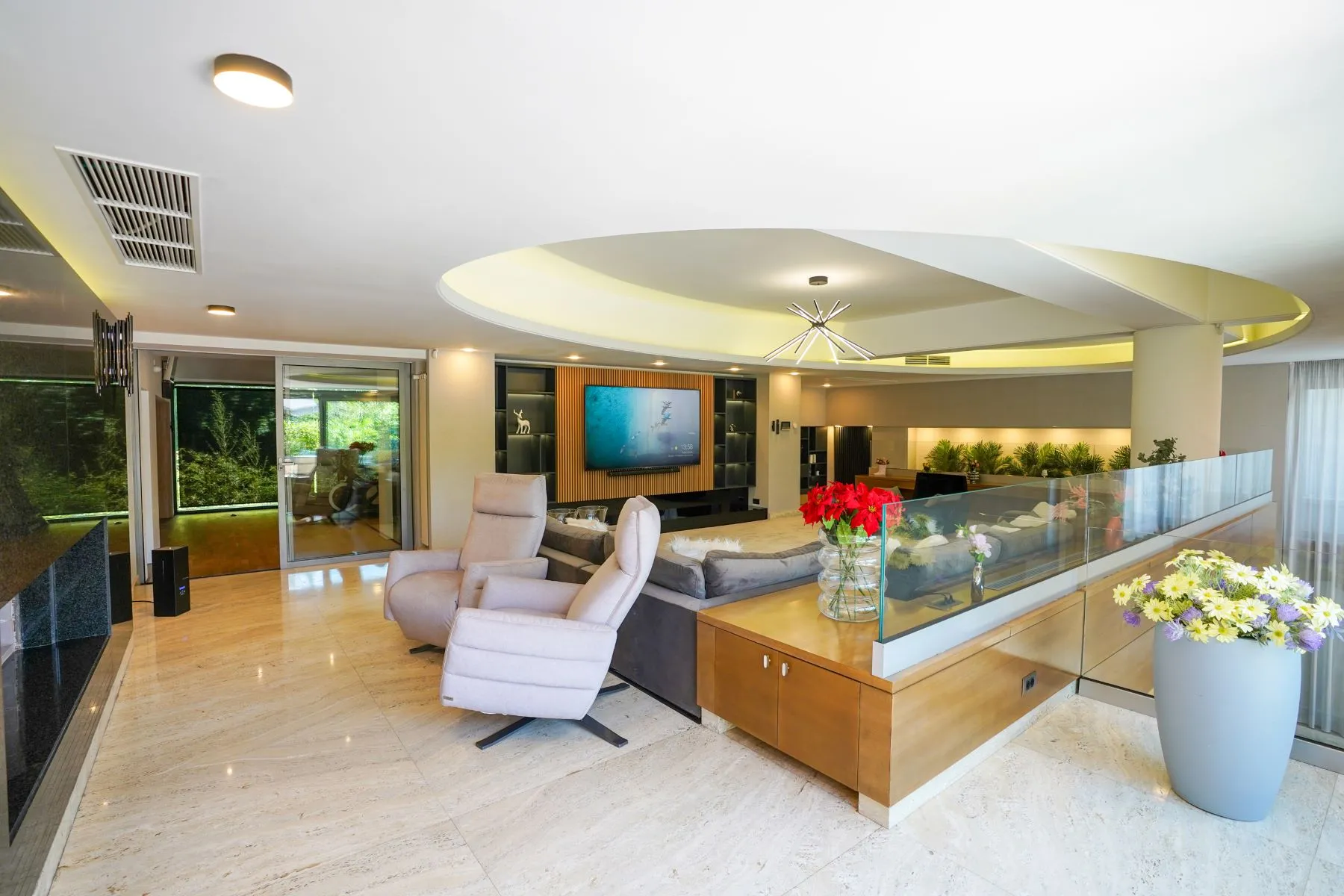 Lakefront living room with armchairs, flowers and doors to the outdoor terrace