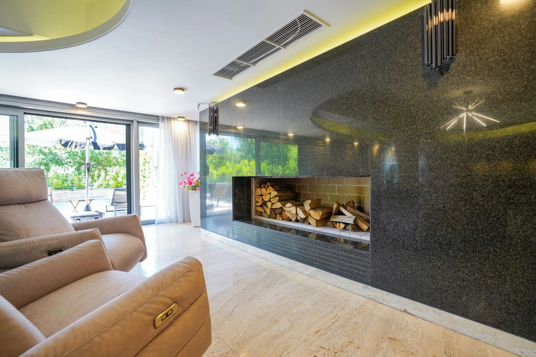 Modern linear fireplace set into a polished stone living-room feature wall