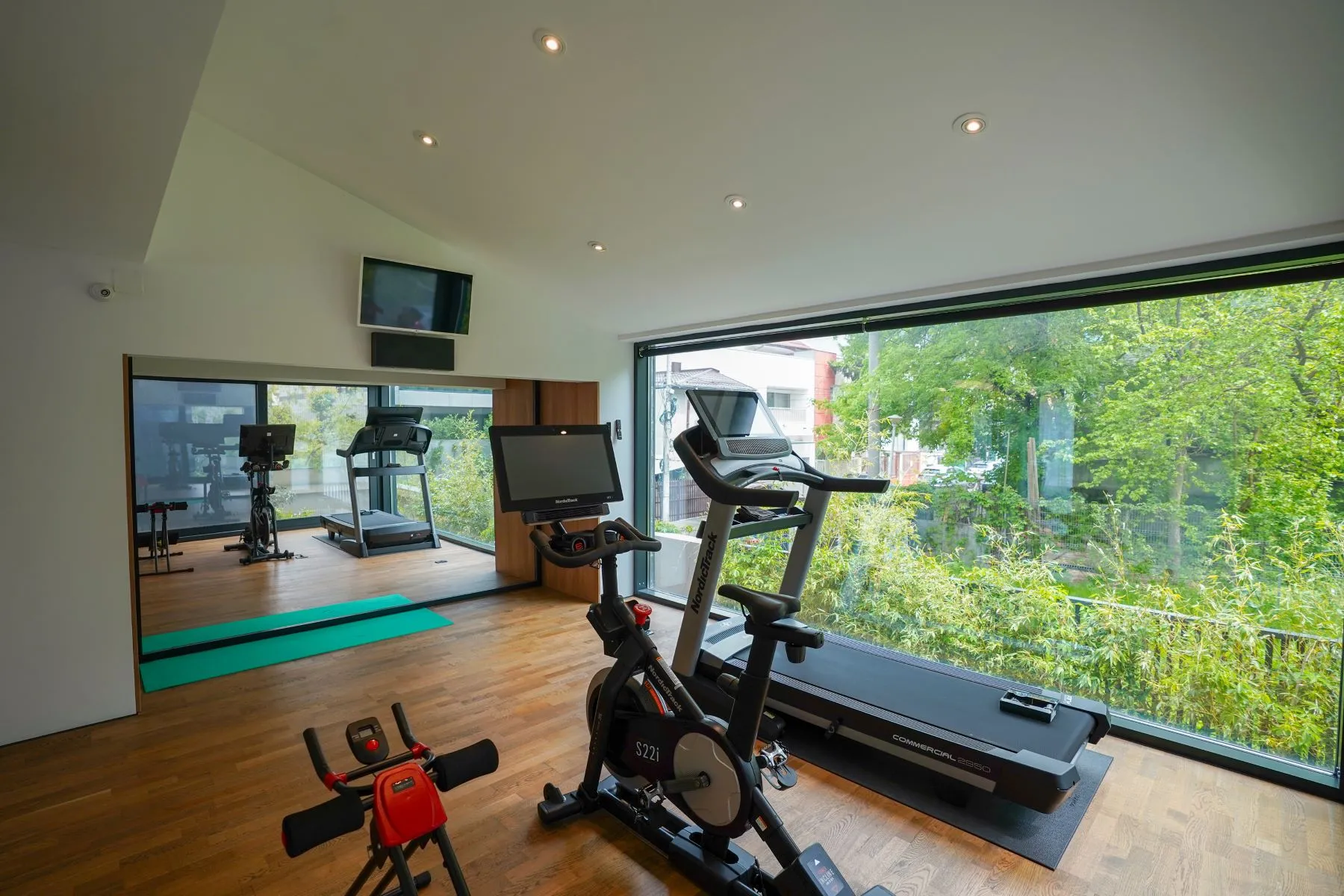 Private fitness room with treadmill, exercise bike and garden-facing windows