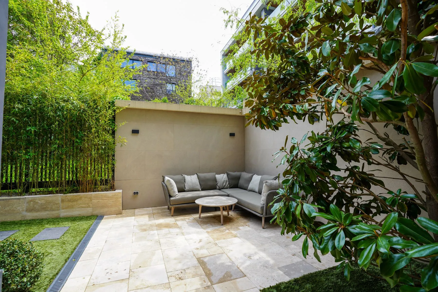 Quiet garden lounge with corner sofa and mature evergreen planting