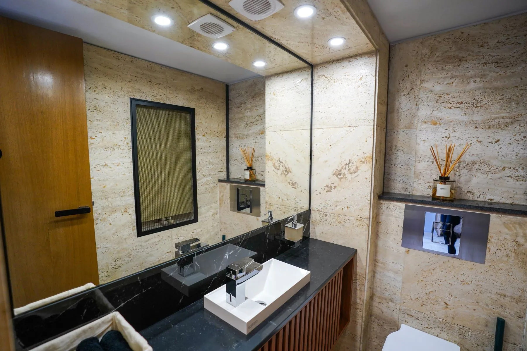 Stone-finished guest cloakroom with vessel basin and concealed fixtures